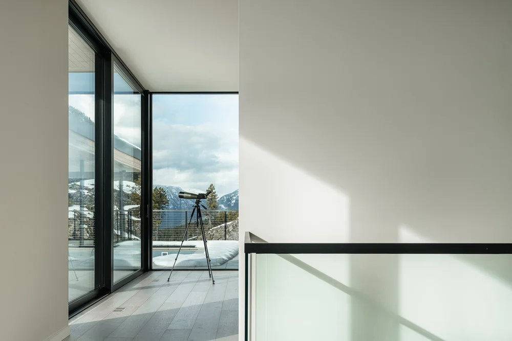 Bedroom looking out through full height glazing to the terrace and mountains