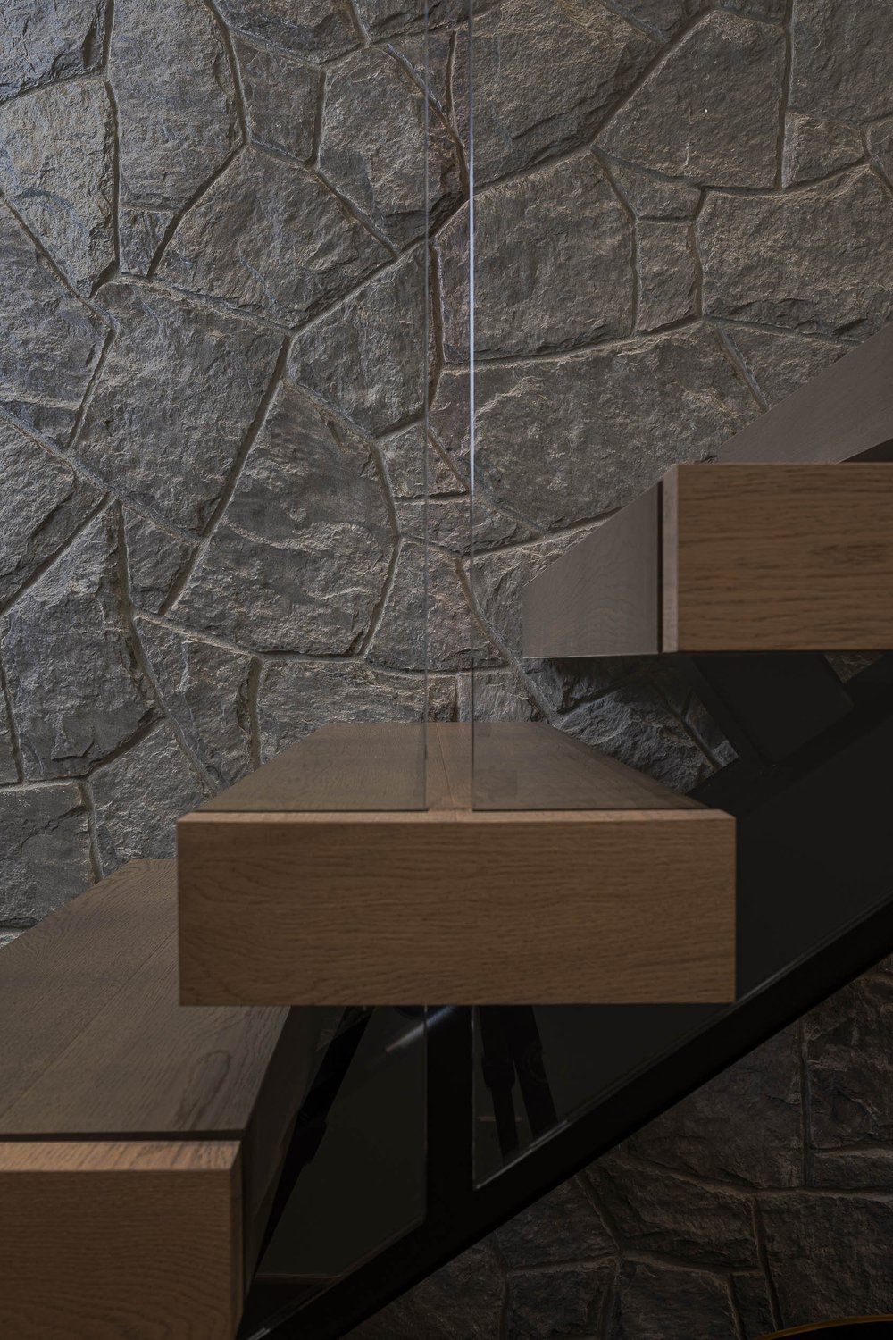 Floating treads cantilevered from a black stringer, rough stone behind