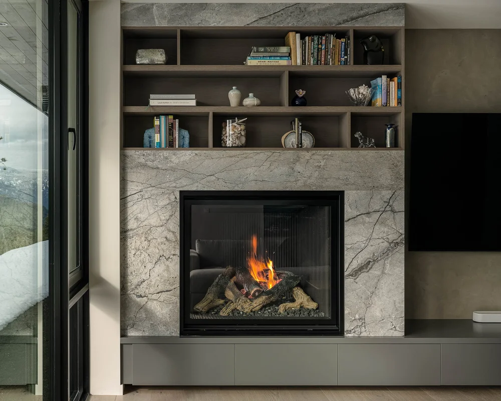 Lit fireplace in a stone surround with open shelving above