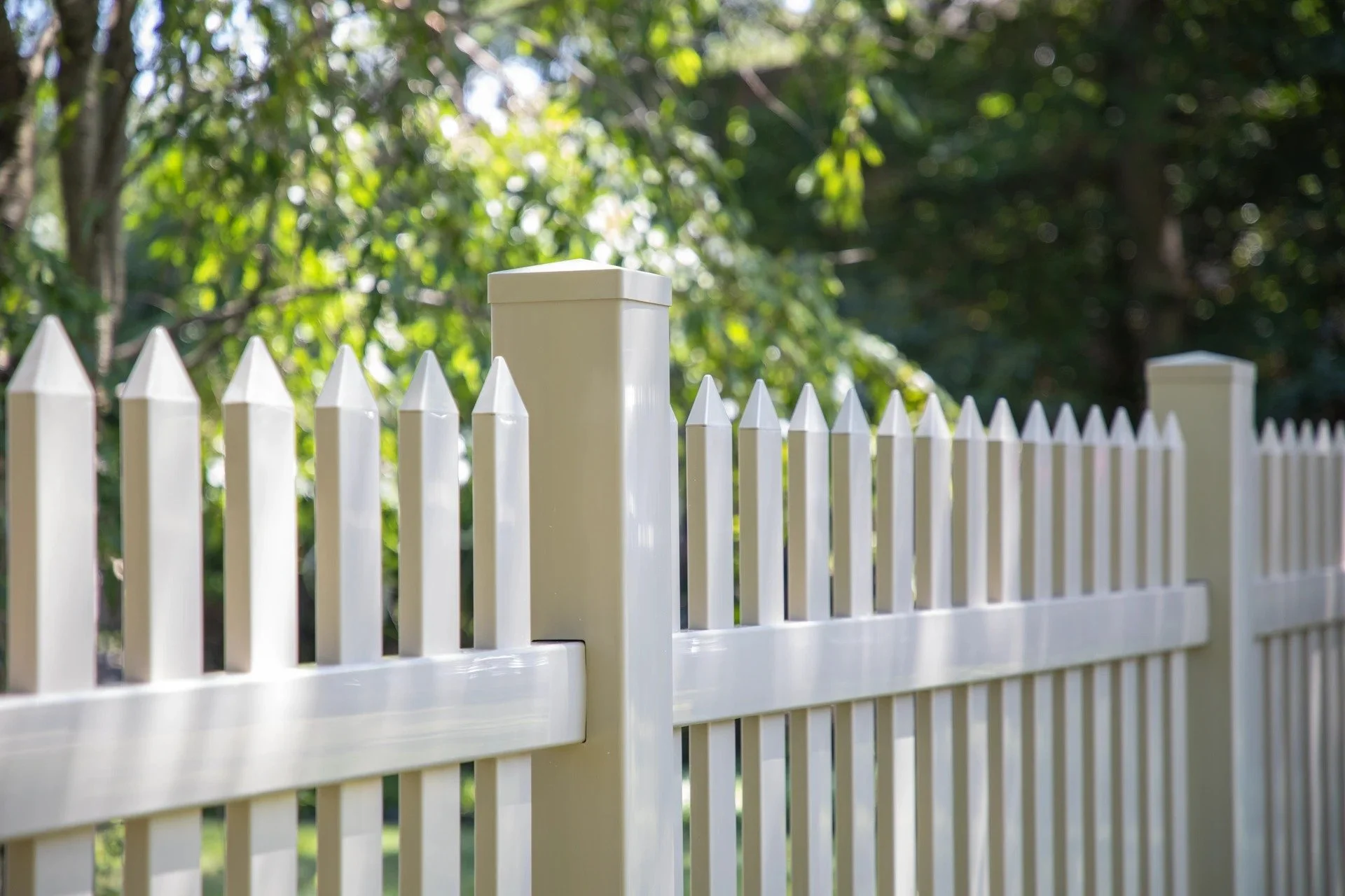 Close-up of tan-and-white vinyl picket fence post and rails in Essex County, NJ — vinyl picket fence, front yard fence.