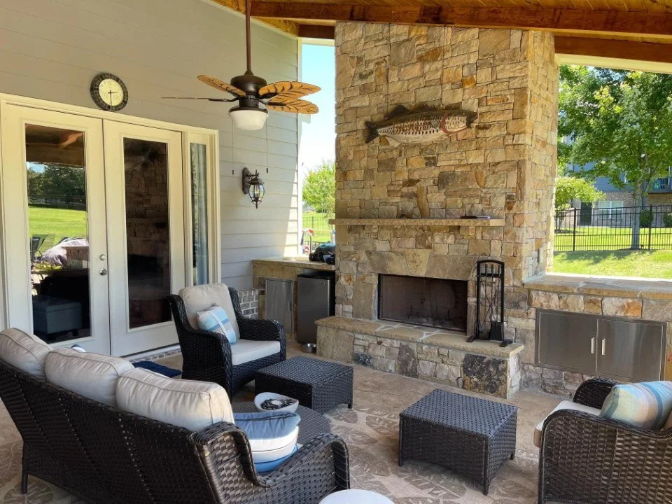 Outdoor living area in Buford, GA with covered fireplace, seating area, and lighting designed by local hardscape company