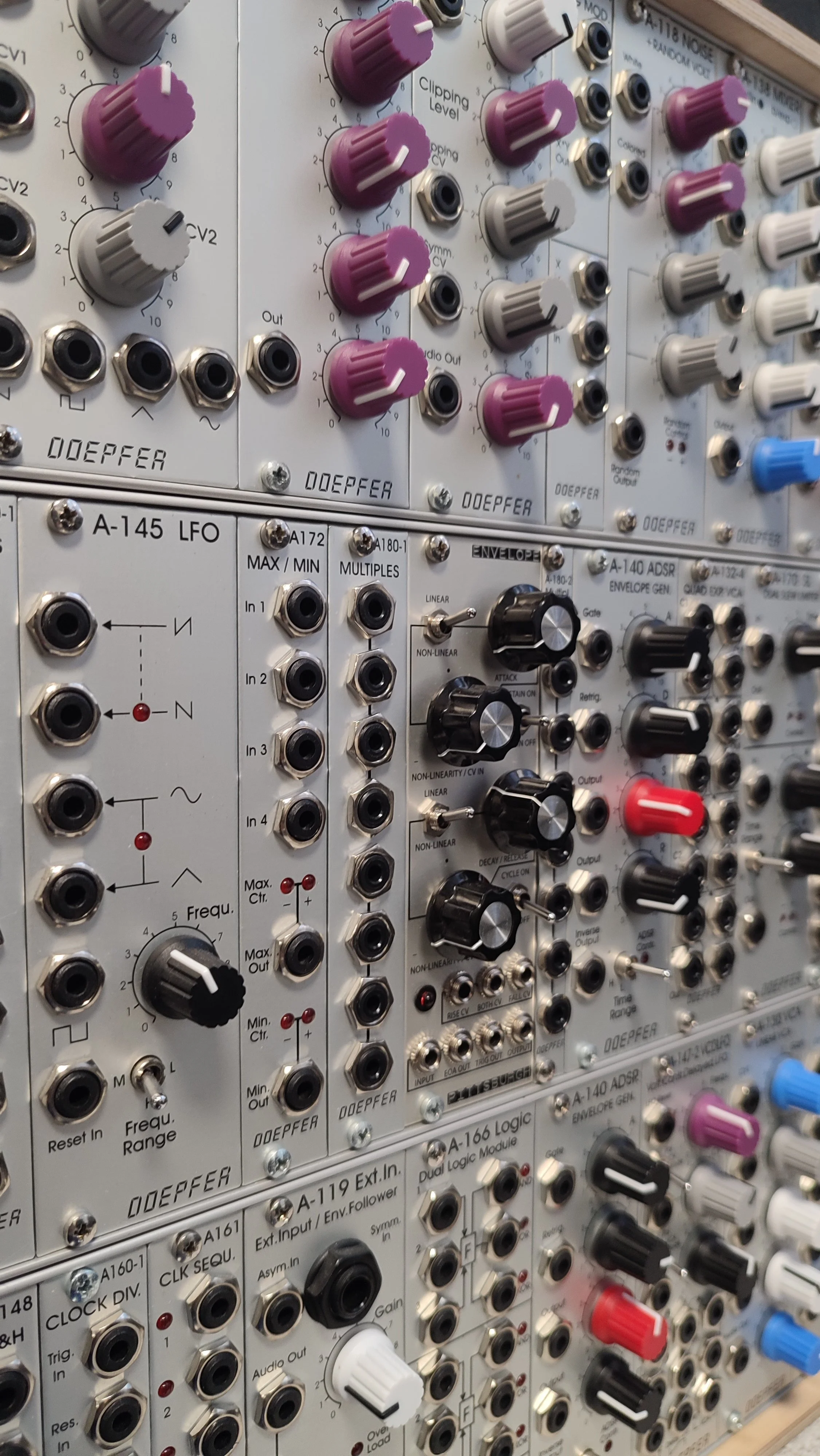 Close-up of a modular synthesizer with various knobs, switches, and input/output jacks, labeled with technical details.