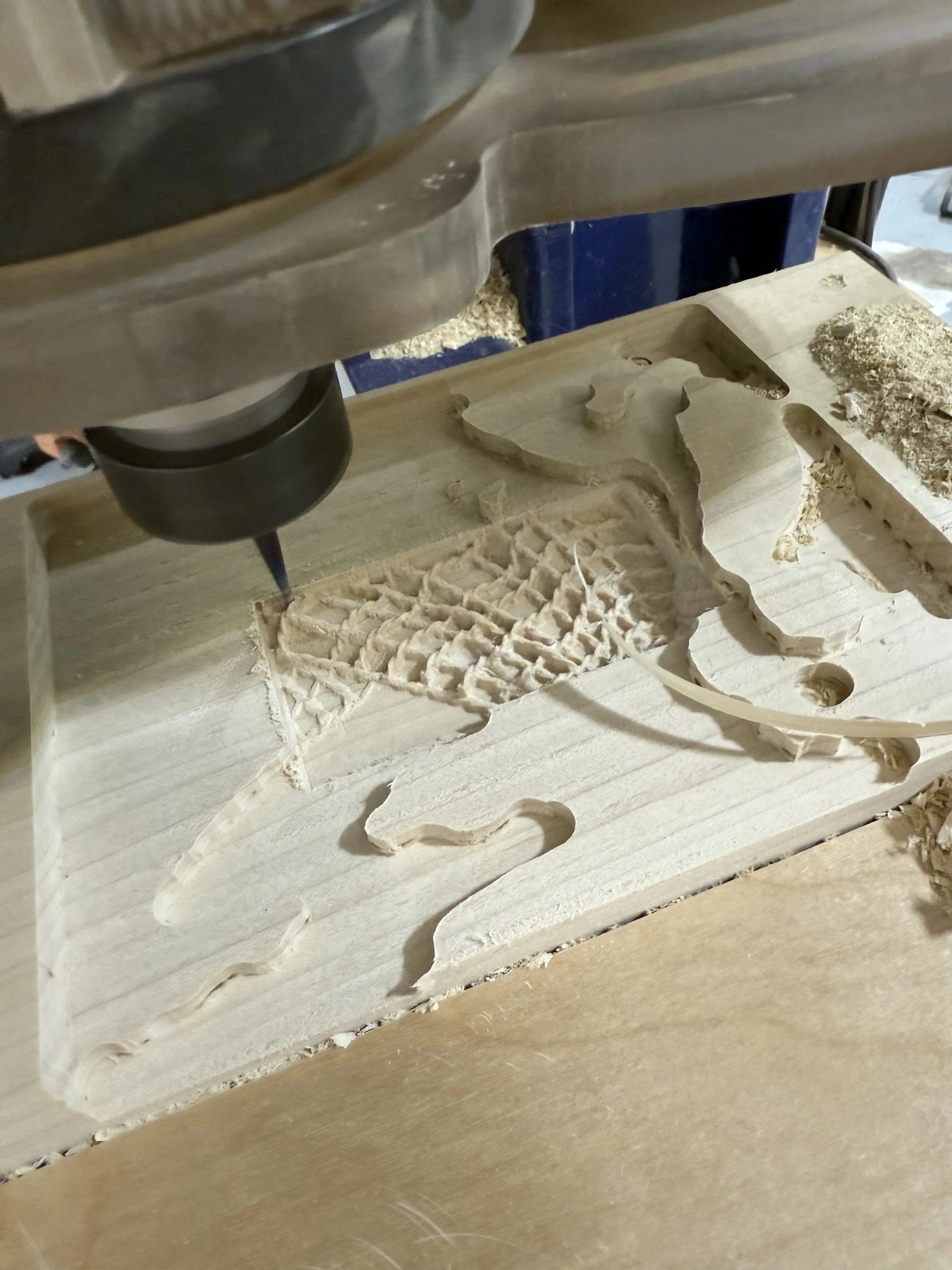 A CNC router carving a wooden panel with a design featuring a whale and a fish.