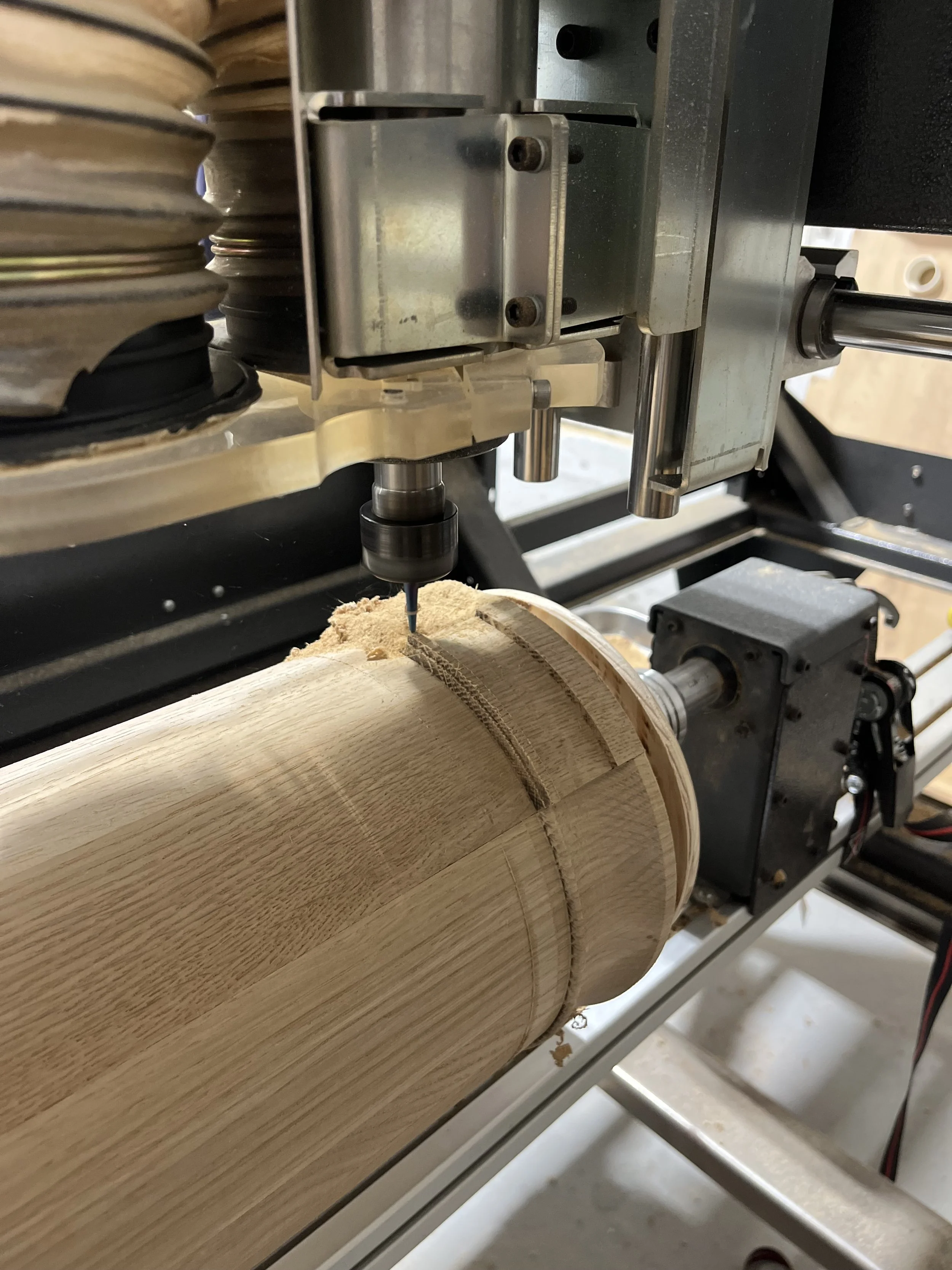 A CNC router machine carving a circular groove into a piece of light-colored wood.