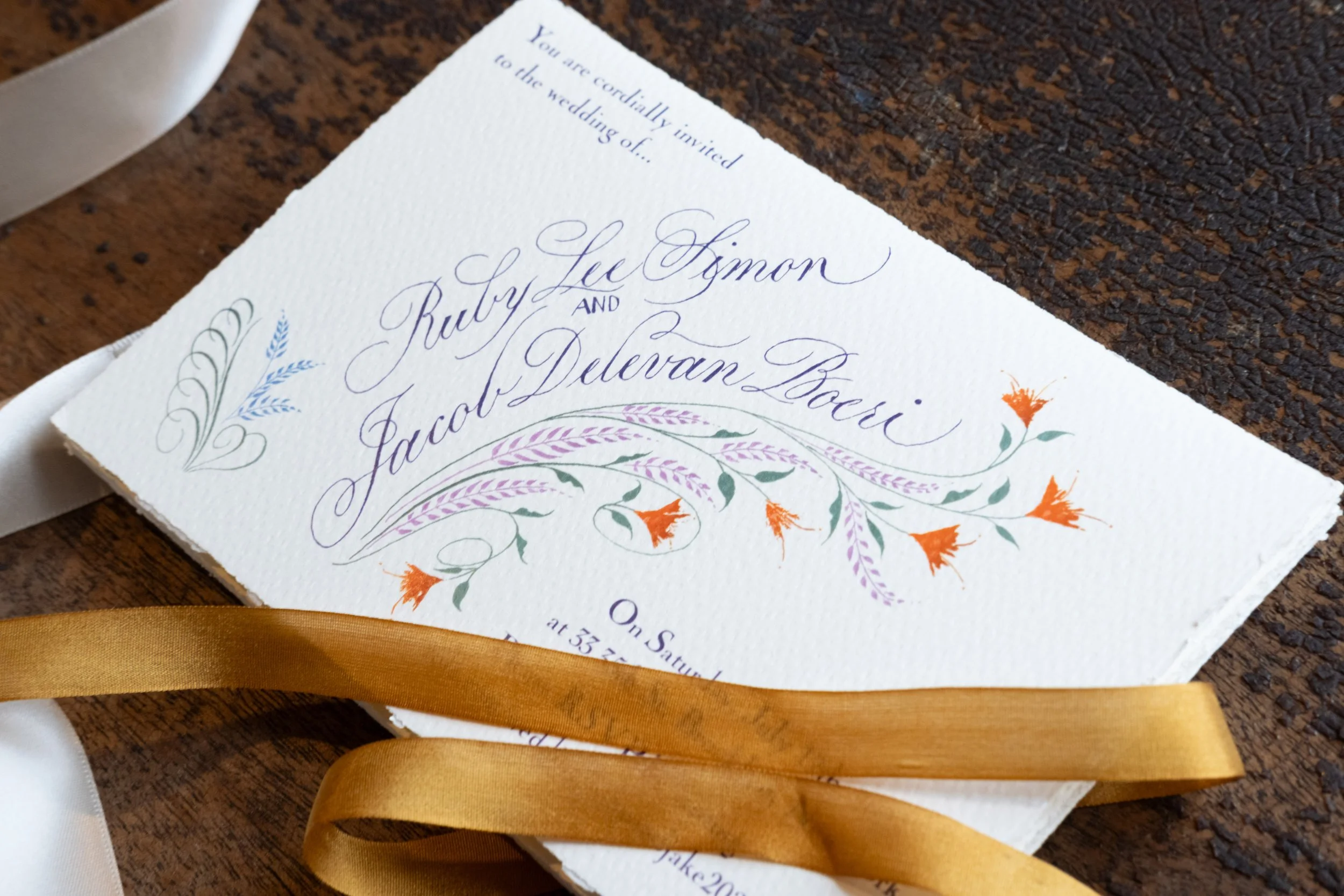 Ruby invite gold ribbon on wood.jpg