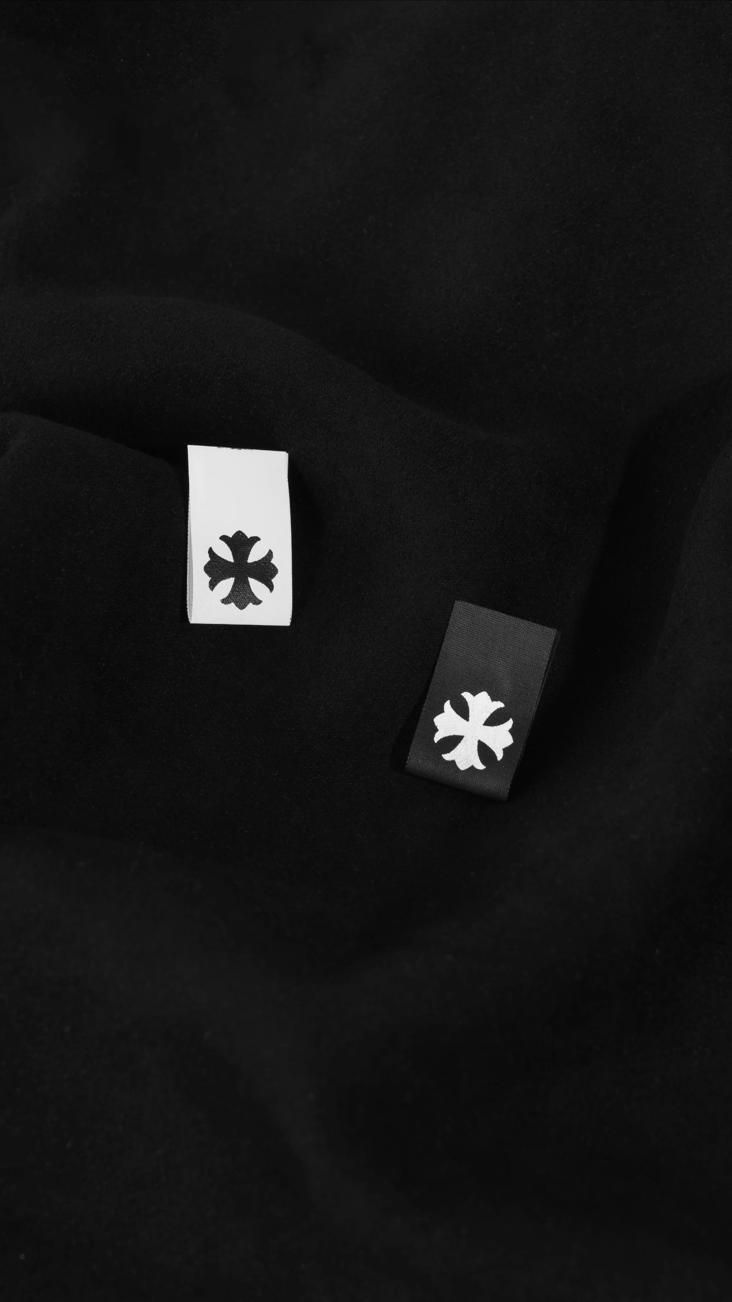 Close-up of two clothing tags with black and white logos inside a black garment.