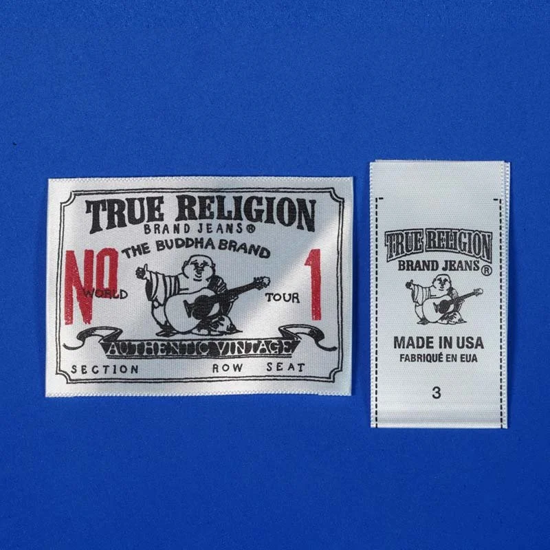 Two clothing tags for True Religion Brand Jeans, one larger with a cartoon bear playing guitar and others with text, and a smaller one with similar design and text indicating made in USA.