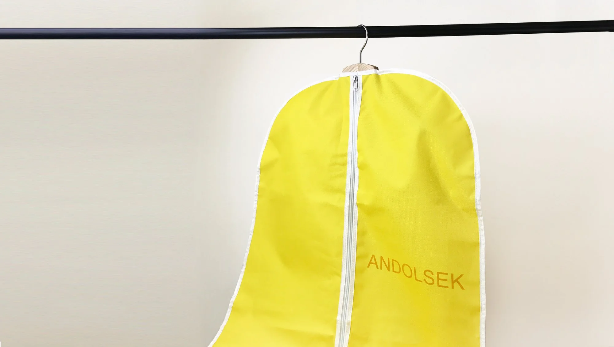 Yellow inflatable safety jacket with the name 'ANDOLSEK' printed on it, hanging on a black rail against a plain background.