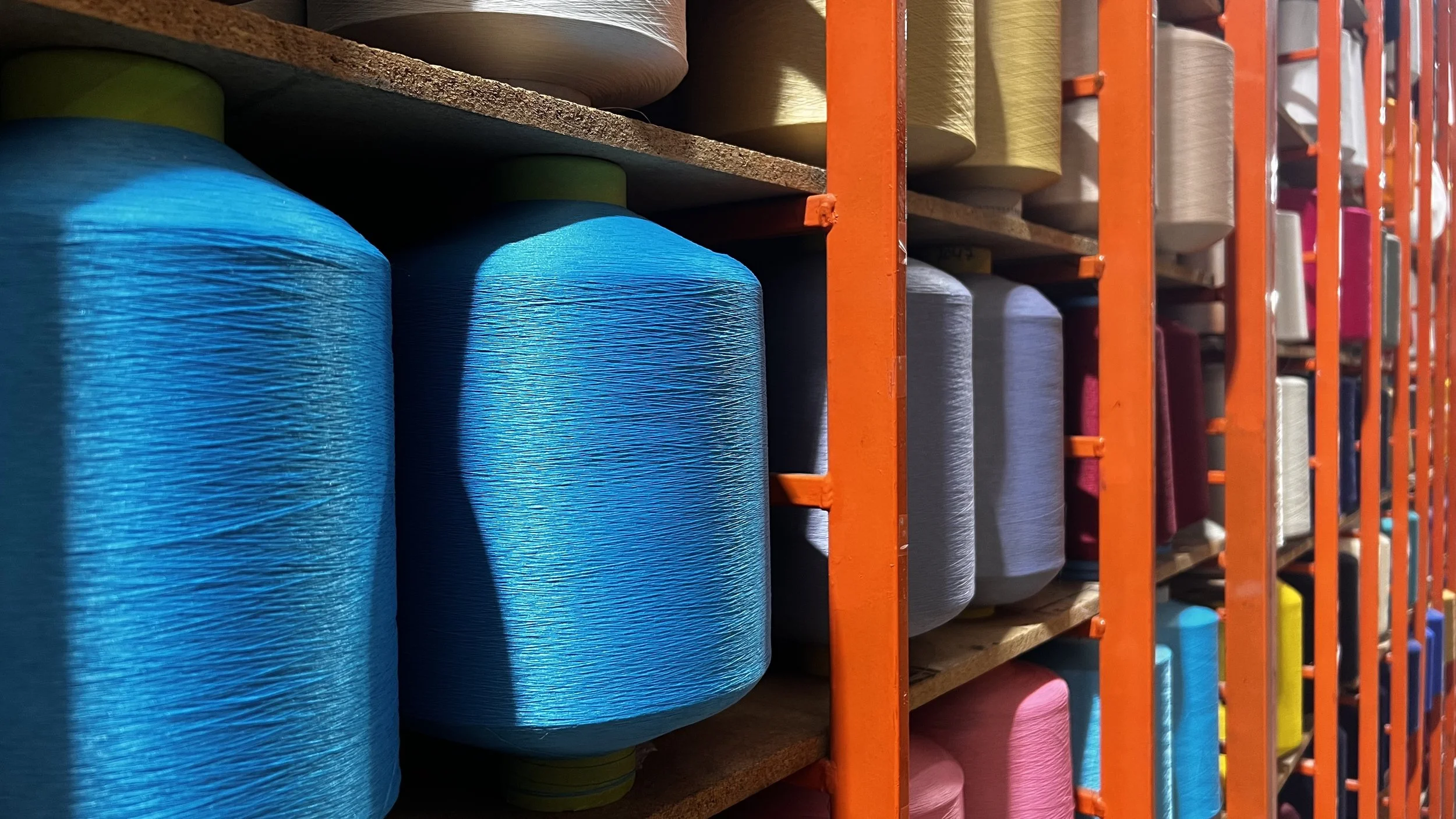 Colorful spools of thread stored on shelves in a fabric or textile store.