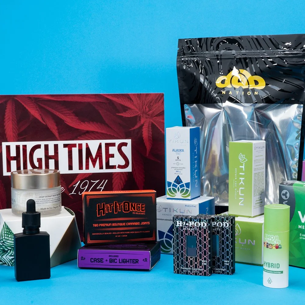 Assorted cannabis and cannabis accessories, including product packaging, a small black dropper bottle, a jar, and boxes of containers on a blue background