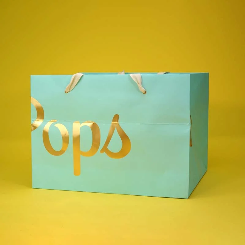 Light blue shopping bag with gold lettering spelling 'pop' against a yellow background.