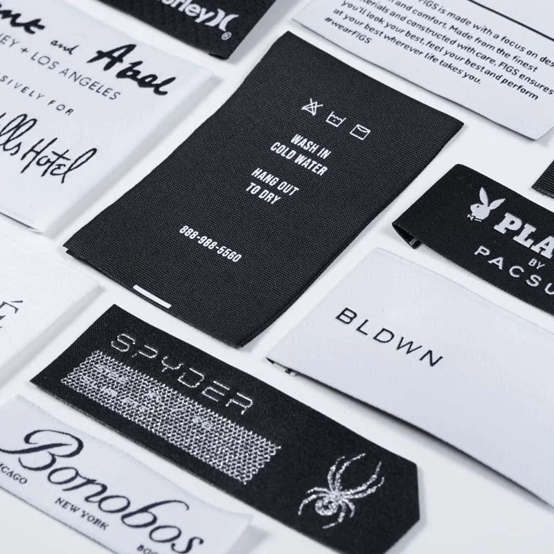 Close-up of various fabric care labels and clothing tags with instructions and brand names.