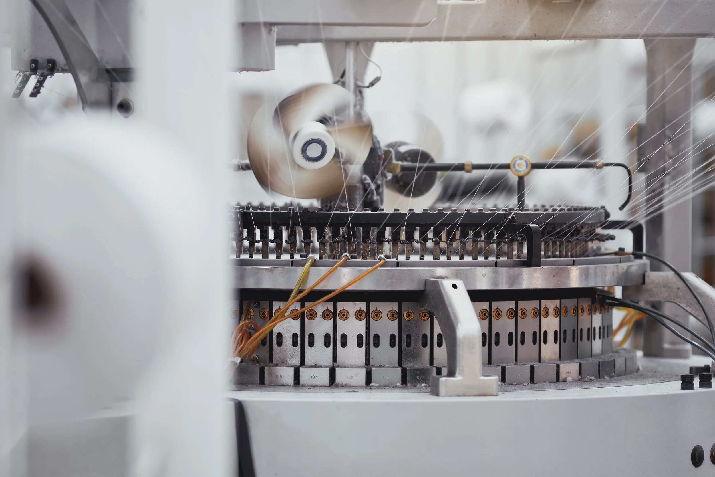 Close-up of a textile machine spinning or weaving fibers with a focused view of the mechanical parts and threads.