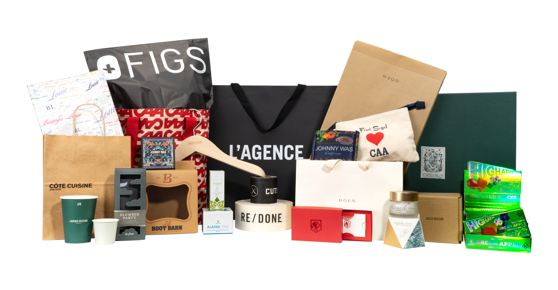 A collection of various gift bags, boxes, and packaging with branded items, including a tree-shaped candle, a purse, a spray bottle, and decorative boxes, arranged on a flat surface.