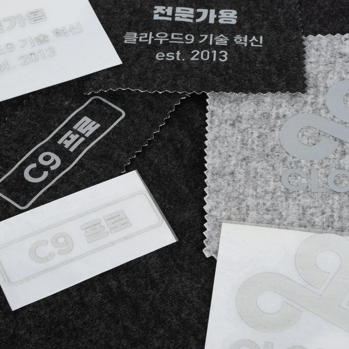 Cloth and paper labels with Korean text and numerical markings, including 'C9' and '9', on dark and light surfaces.