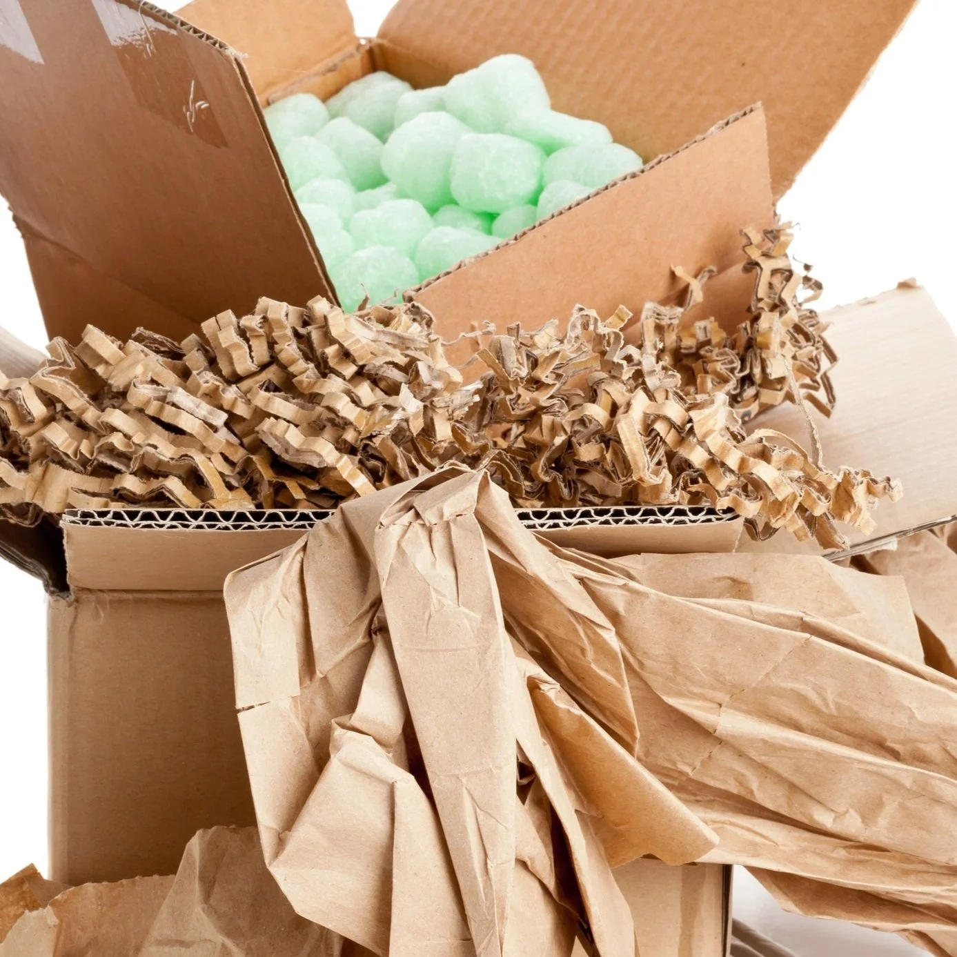 Open cardboard box containing green packing peanuts, crumpled brown packing paper, and shredded paper.