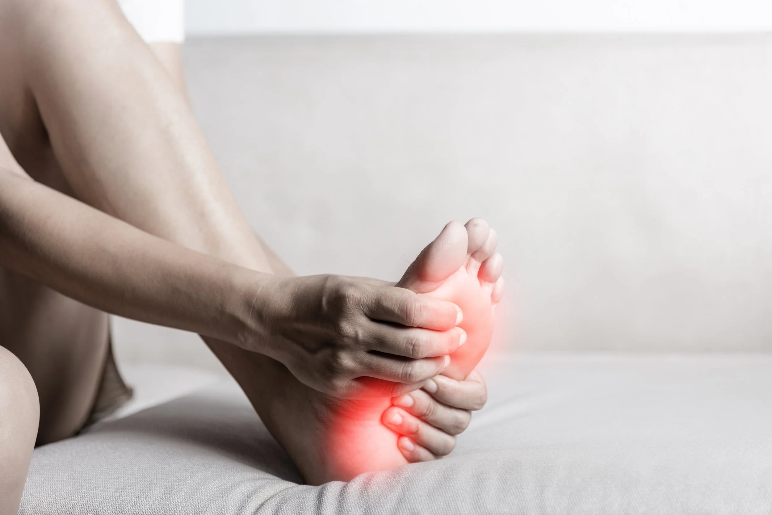 A person touching their lower back, with a red glow indicating pain or discomfort, against a plain white background.