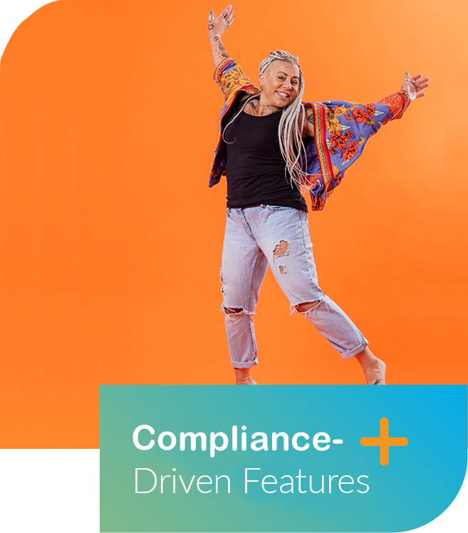 A woman with silver hair and tattoos smiling and dancing against an orange background, wearing a black shirt, distressed jeans, and a colorful embroidered jacket. A text overlay reads "Compliance- Driven Features" with a plus sign.