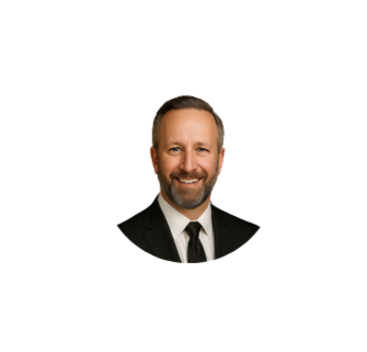 A headshot of a smiling man with a beard, wearing a suit and tie, against a white background.