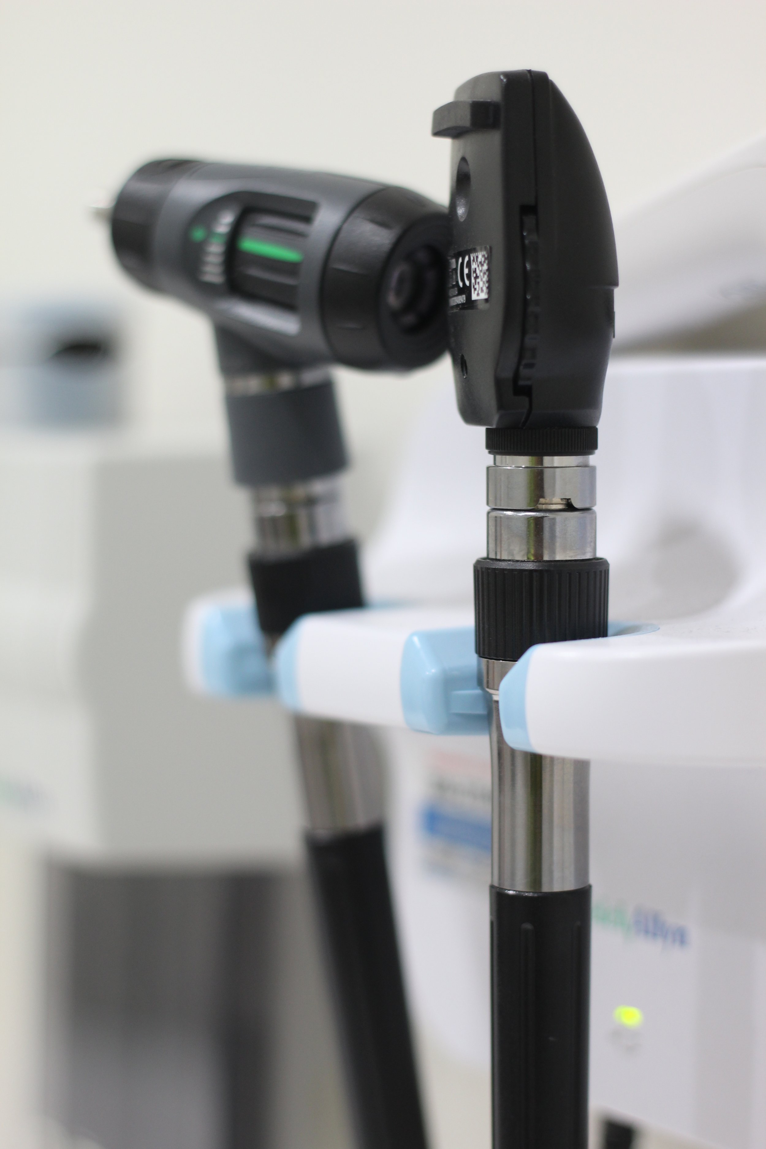 A digital thermometer showing a temperature of 98.6°F, surrounded by medical tools and pills, with a sign that reads 'Primary Care' on a light wooden surface.