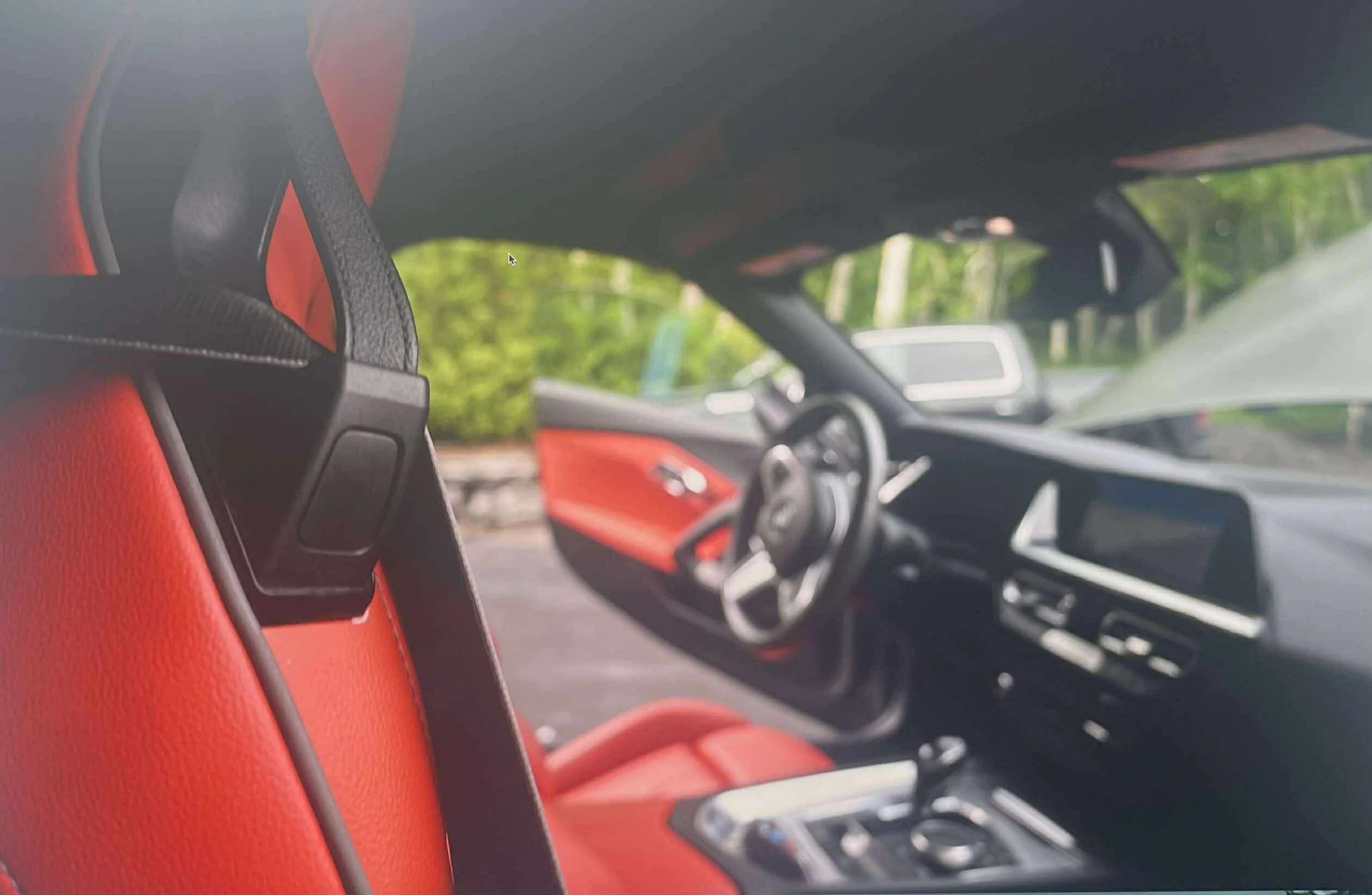 Intérieur d'une voiture moderne avec des sièges en cuir rouge, volant multifonctionnel, et tableau de bord numérique.