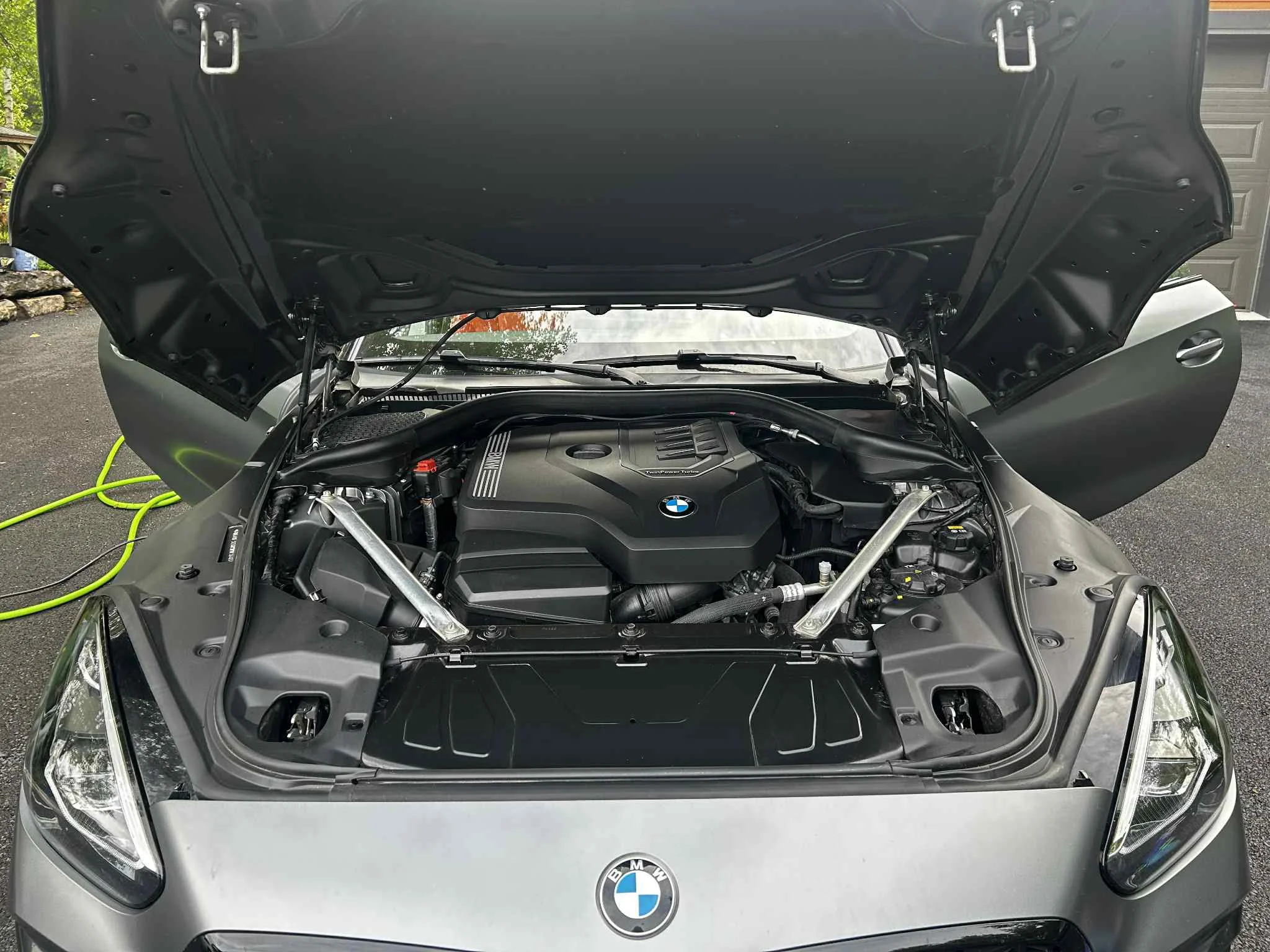 Moteur de voiture BMW sous capot ouvert, siège arrière visible