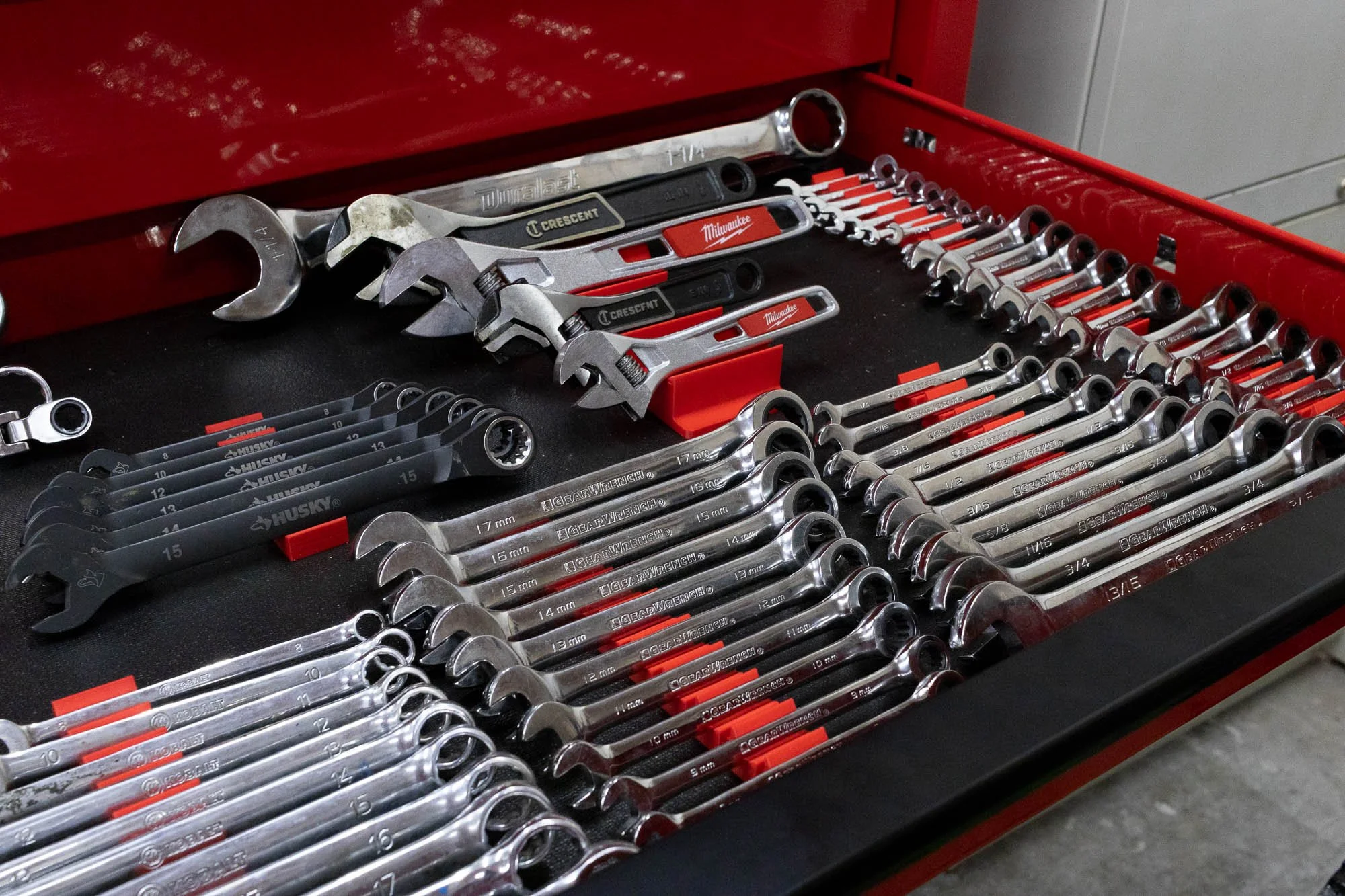 Toolbox containing various sizes of open-end wrenches and combination wrenches arranged neatly.