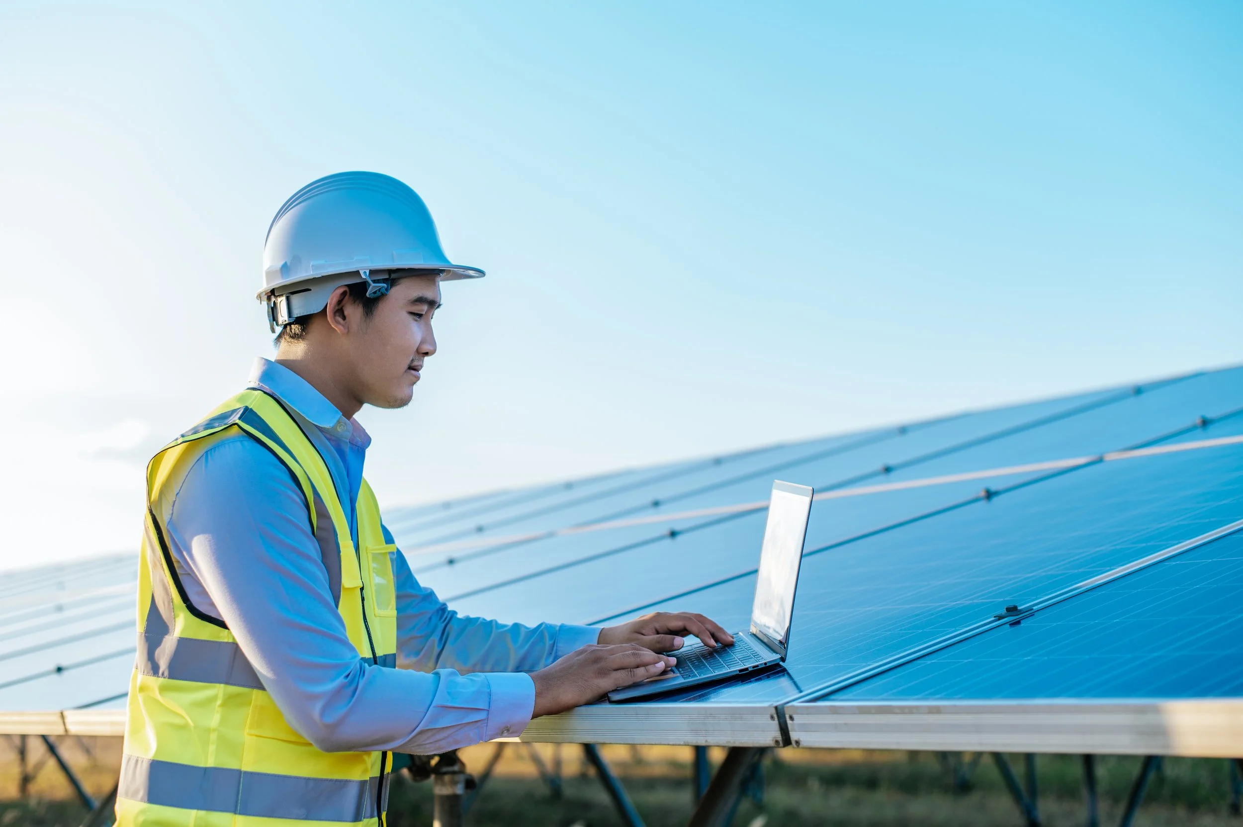 solar-panel-recycling-young-asian-inspector-engineer-man-use-laptop-computer-working-solar-farm-technician-supervisor-male-white-helmet-checking-operation-sun-photovoltaic-solar-panel-station-copy-space