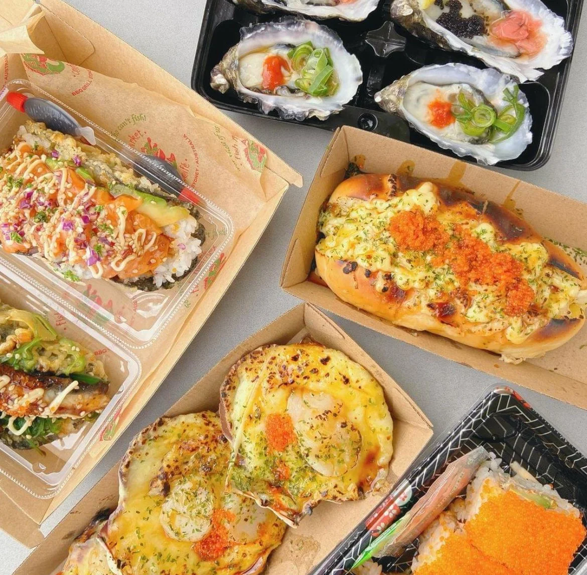 An assortment of Japanese sushi, oysters, baked bread with toppings, and sushi rolls on a table.