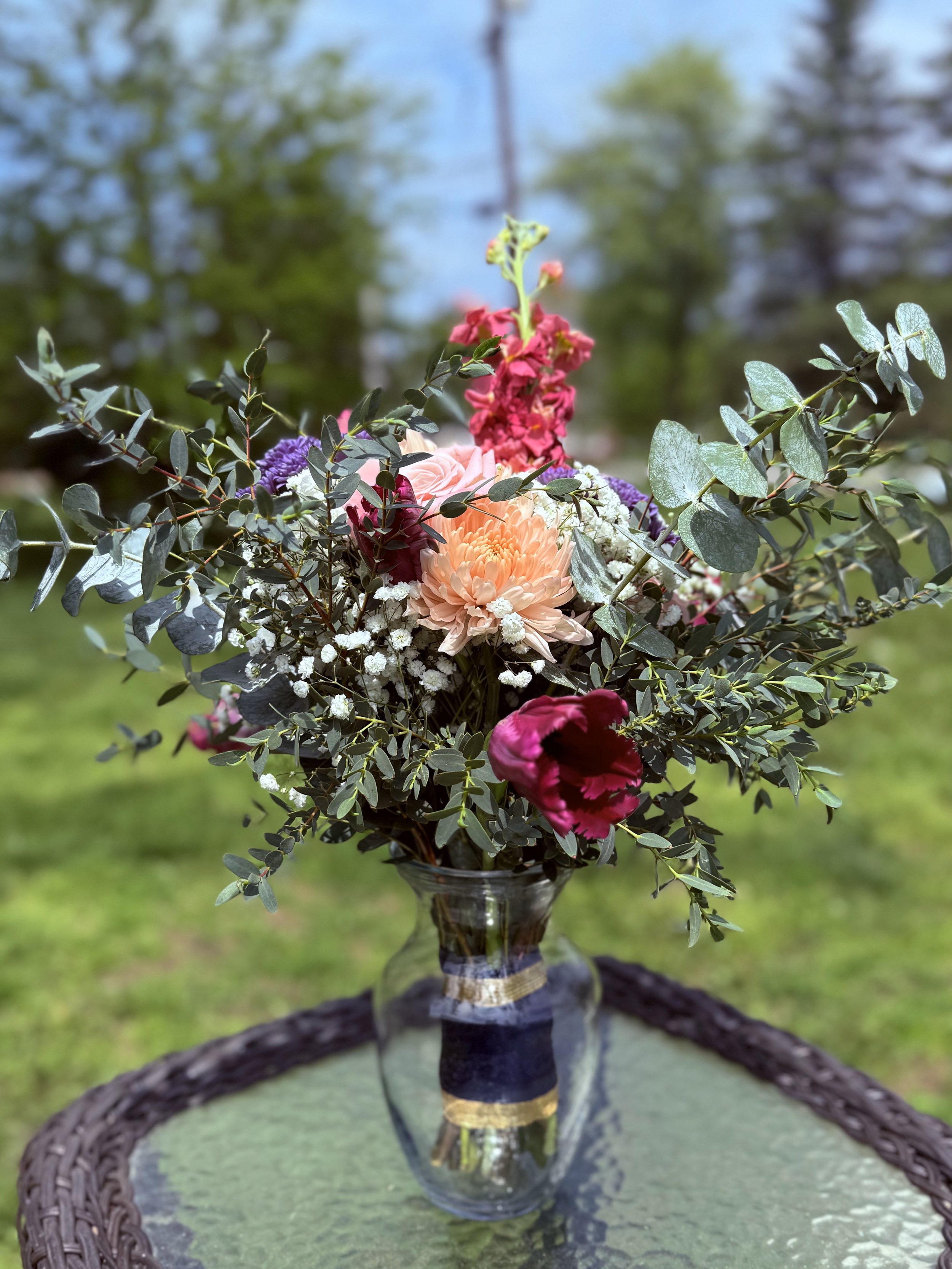 Bouquet of colorful flowers in a glass vase on an outdoor table