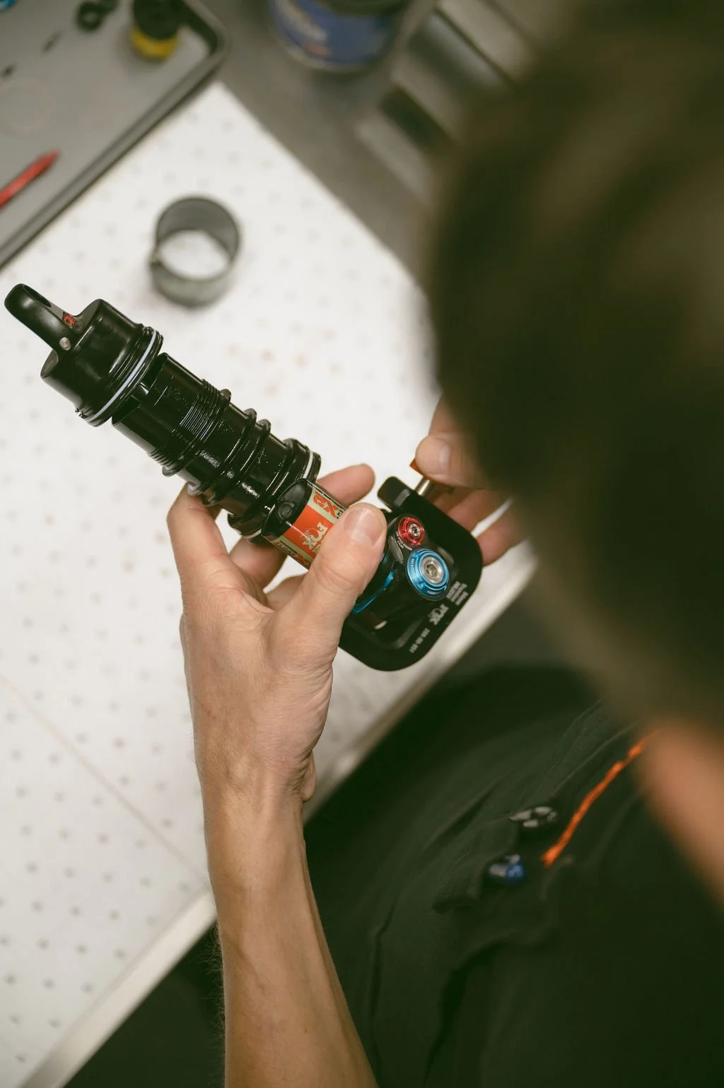 Person holding a bike suspension fork with a shock pump attached, inflating it.