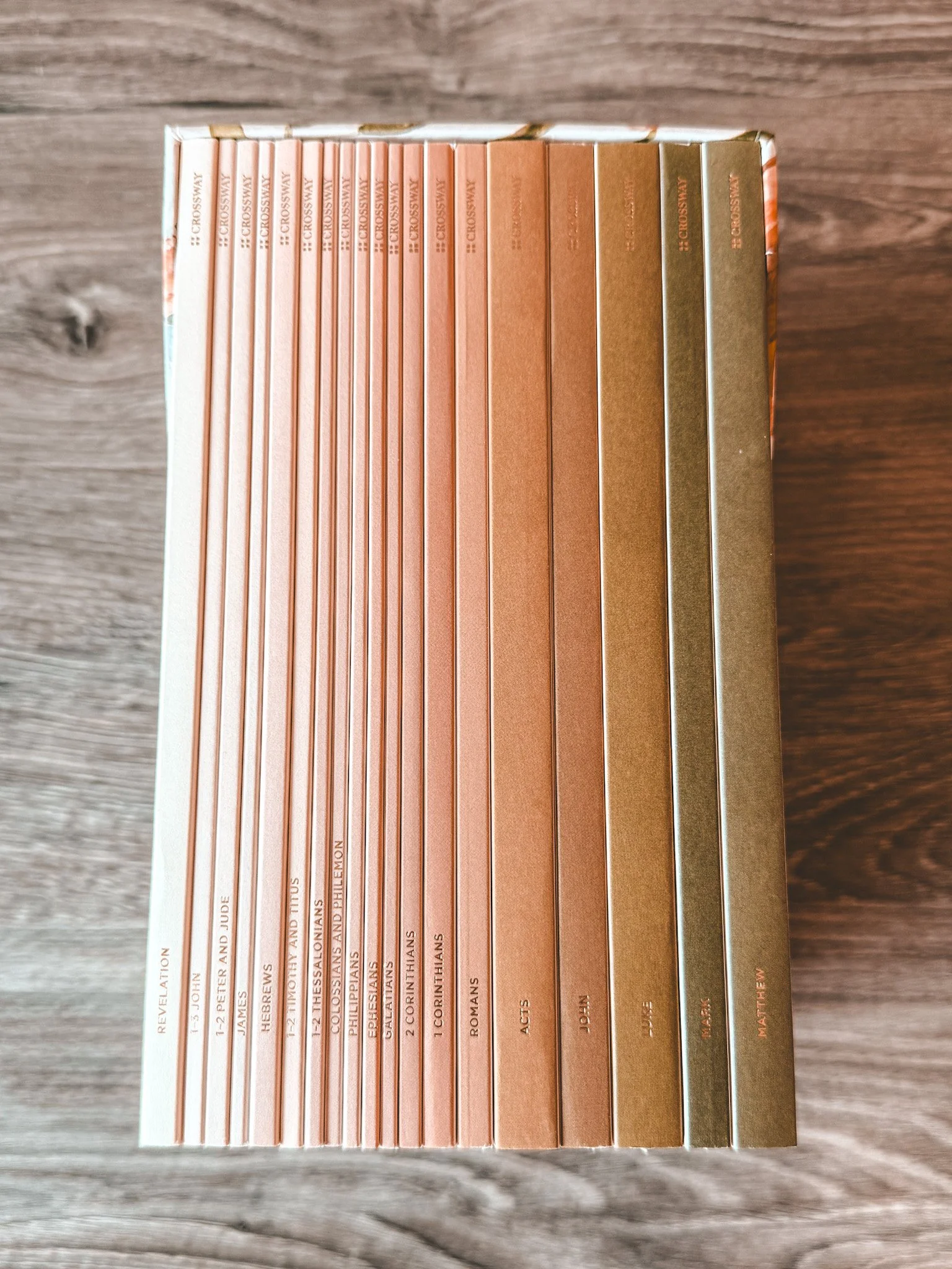 A collection of paperback books arranged vertically on a wooden surface, with titles visible on the spines.