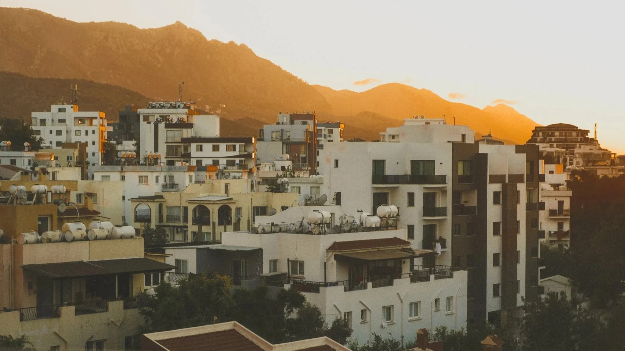The sun sets on the hills behind a city in the Middle East