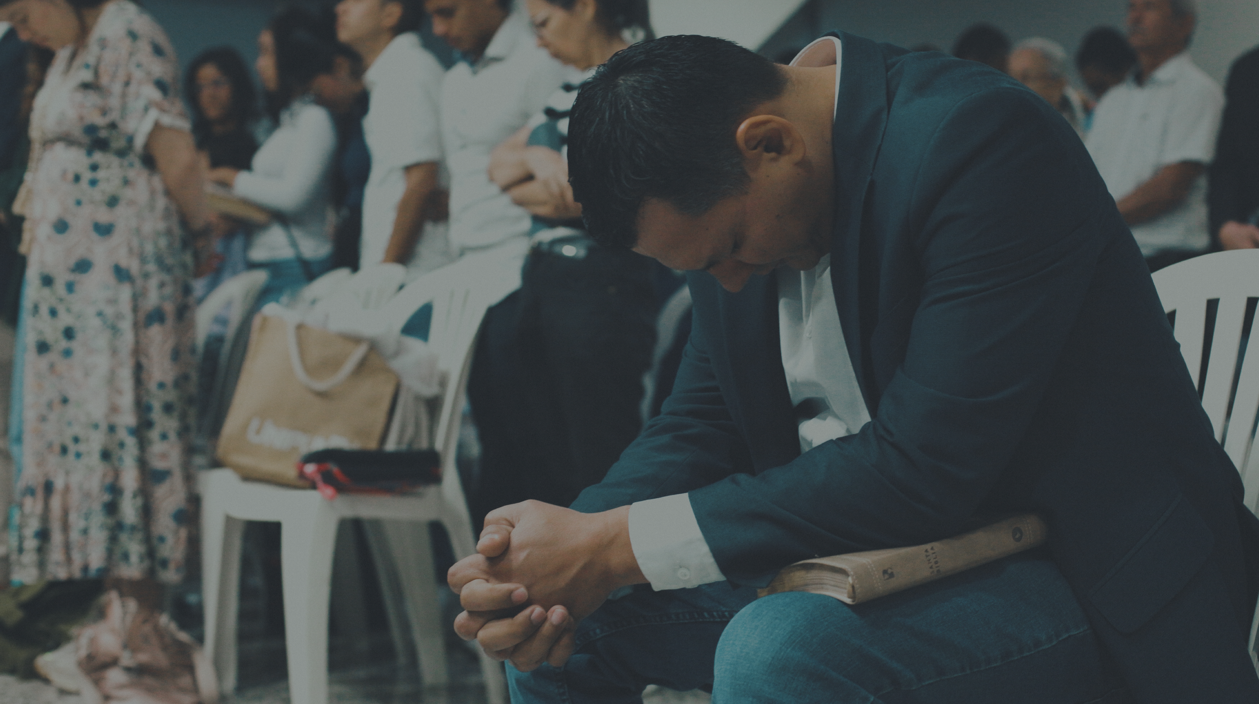 Man praying with a Bible in his lap in a Colombian church