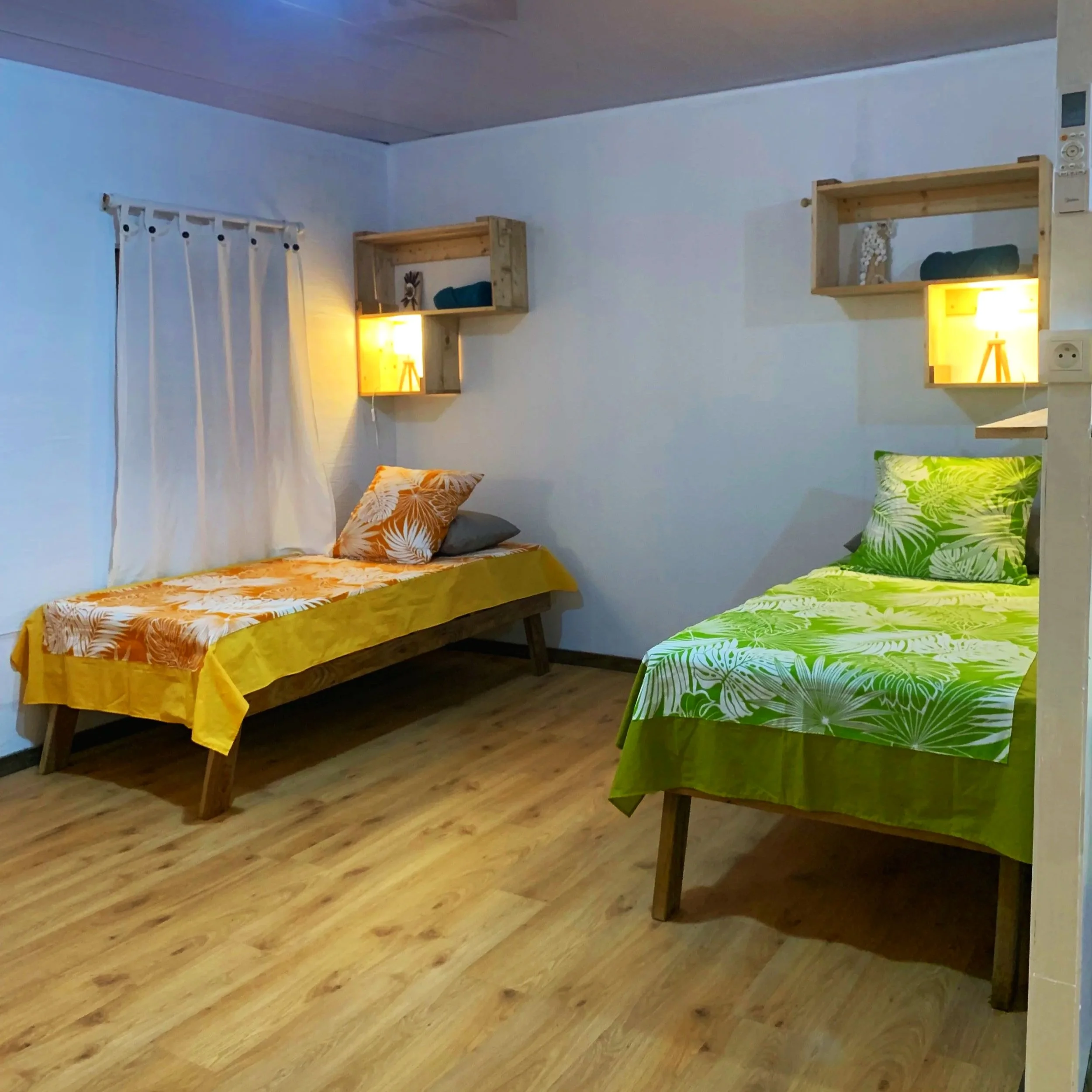 Dortoir lumineux et convivial avec lits individuels colorés, lampes de chevets, serviettes et couverture à Rangiroa