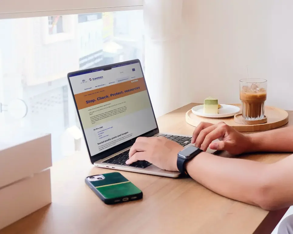 Man browsing Scamwatch translated resourced page on his laptop