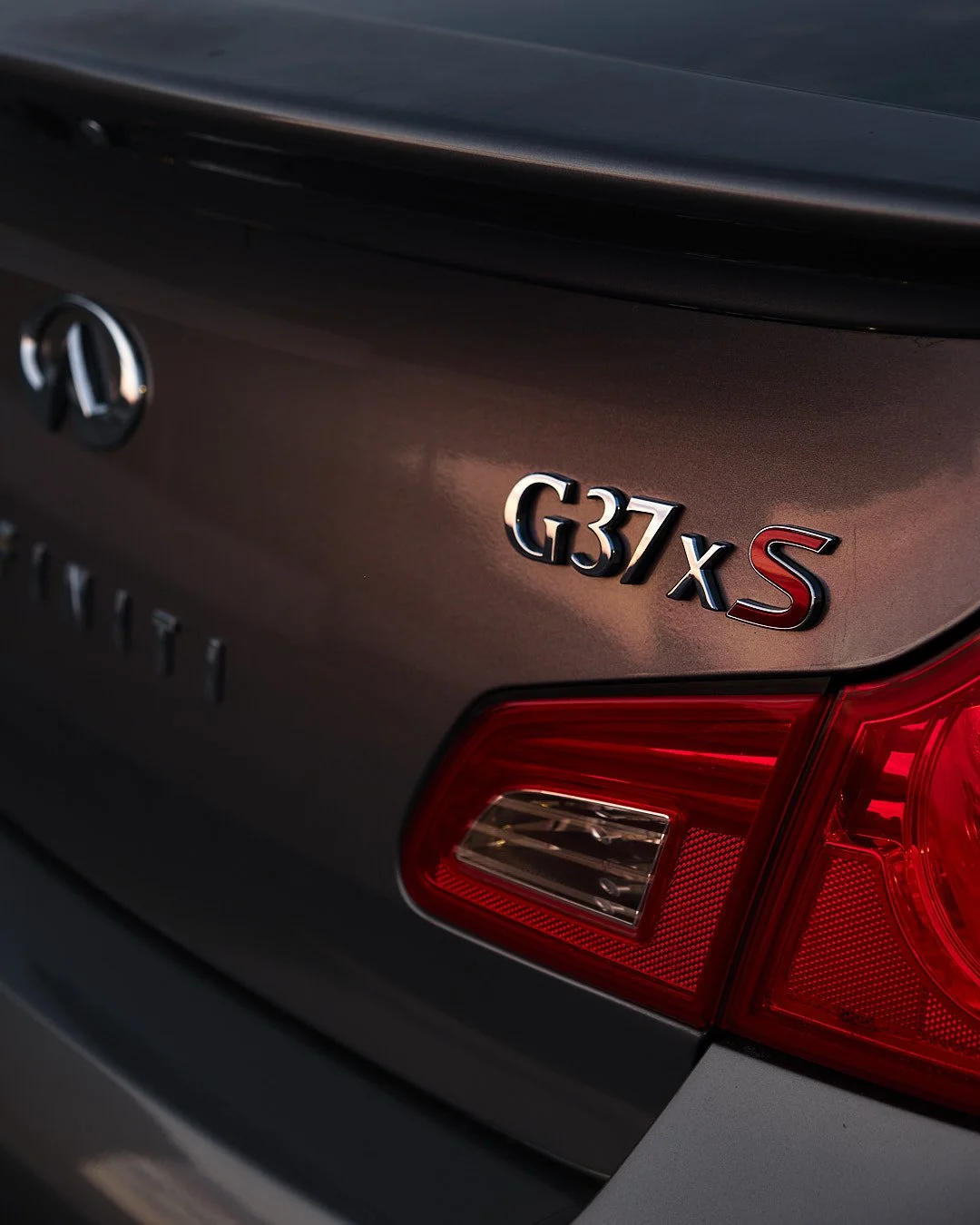 Close-up of the rear badge of a Lexus G37xS vehicle, showing the model name and part of the tail light.