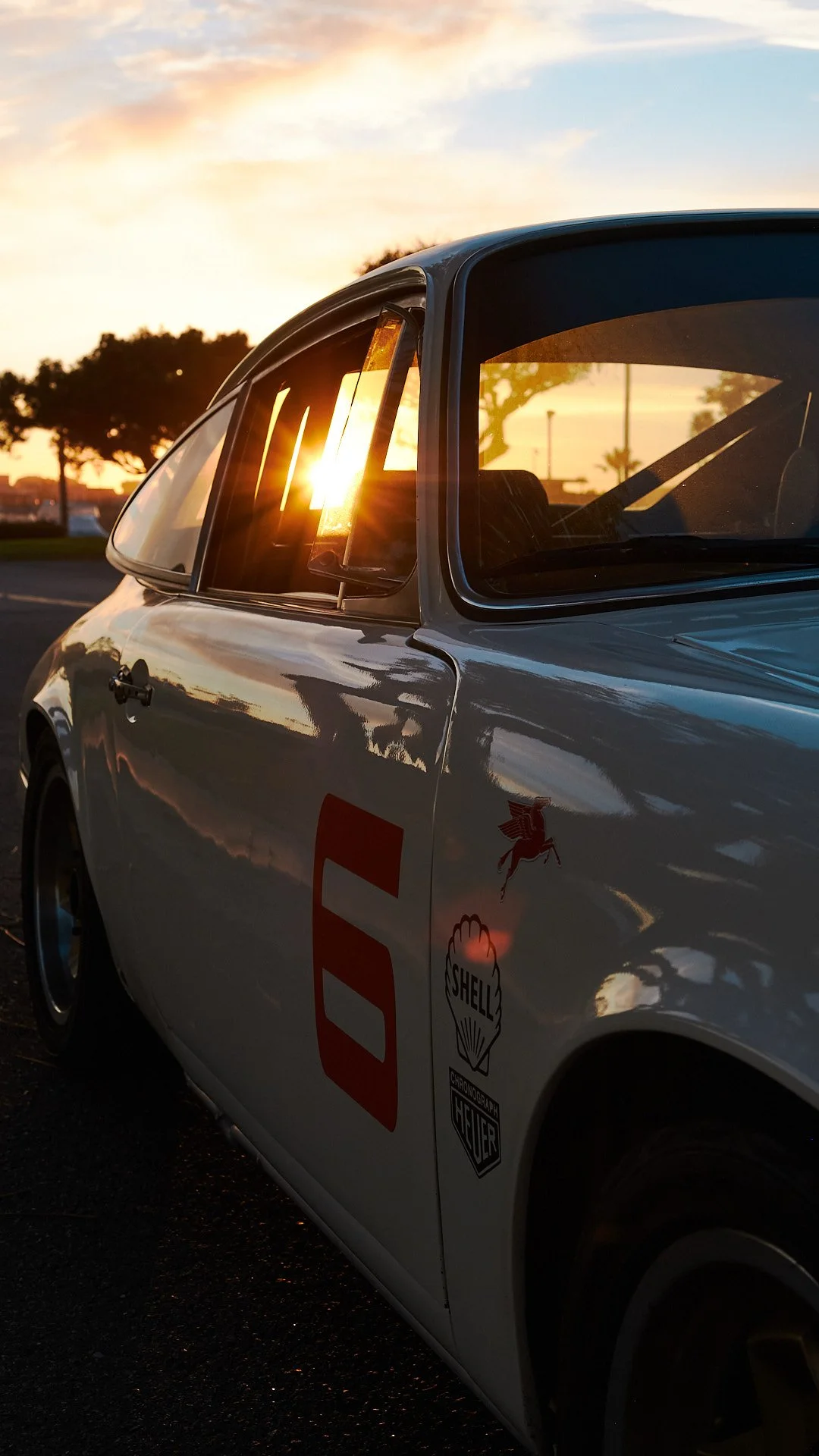 Classic white racing car with red number 5 on the side, parked at sunset.