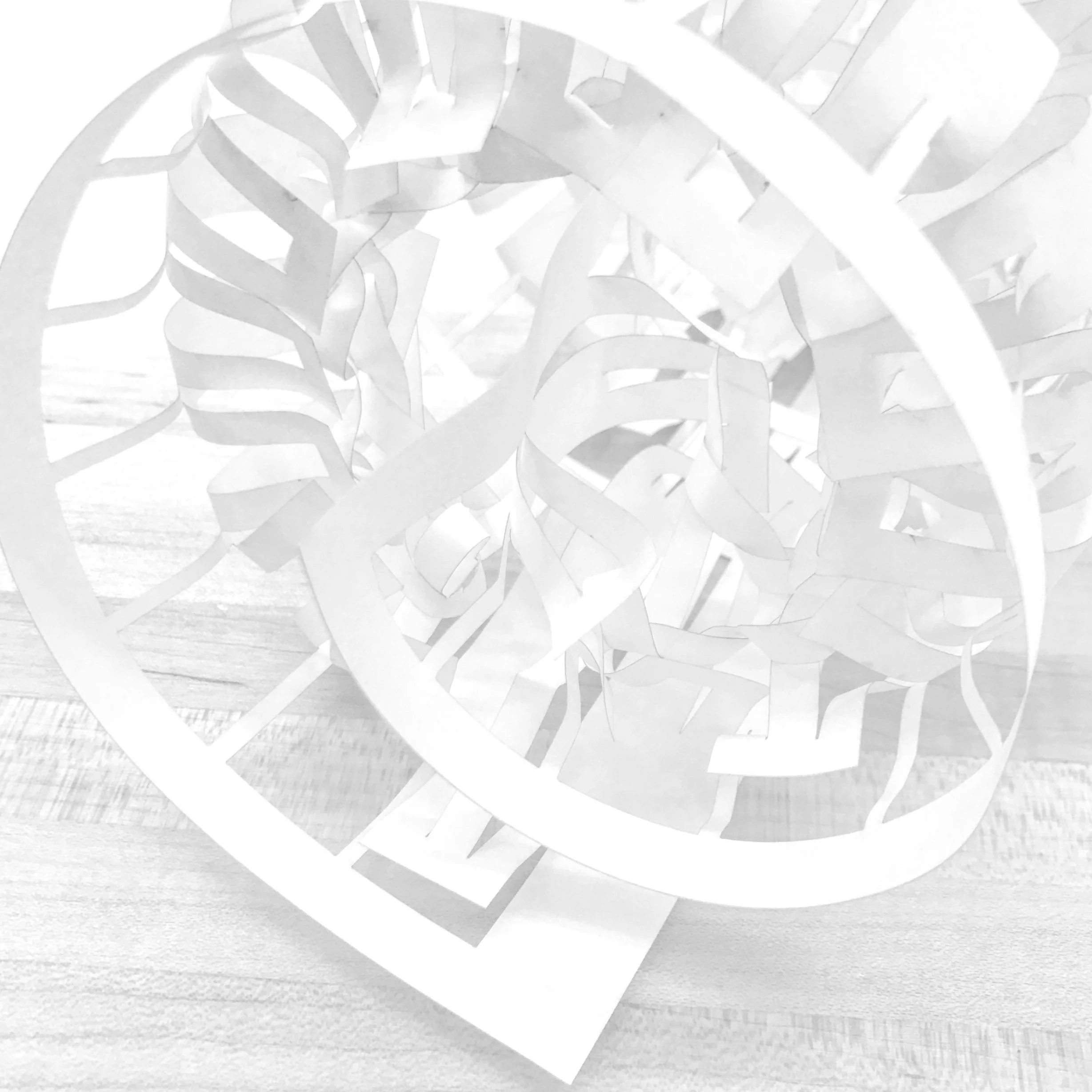 White, intricate paper sculpture with a spiral, organic design resting on a wooden surface.