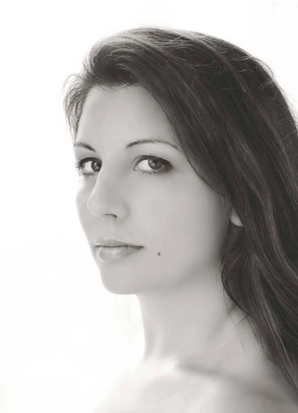 Black and white portrait of a woman with long dark hair, light makeup, looking slightly to the side.