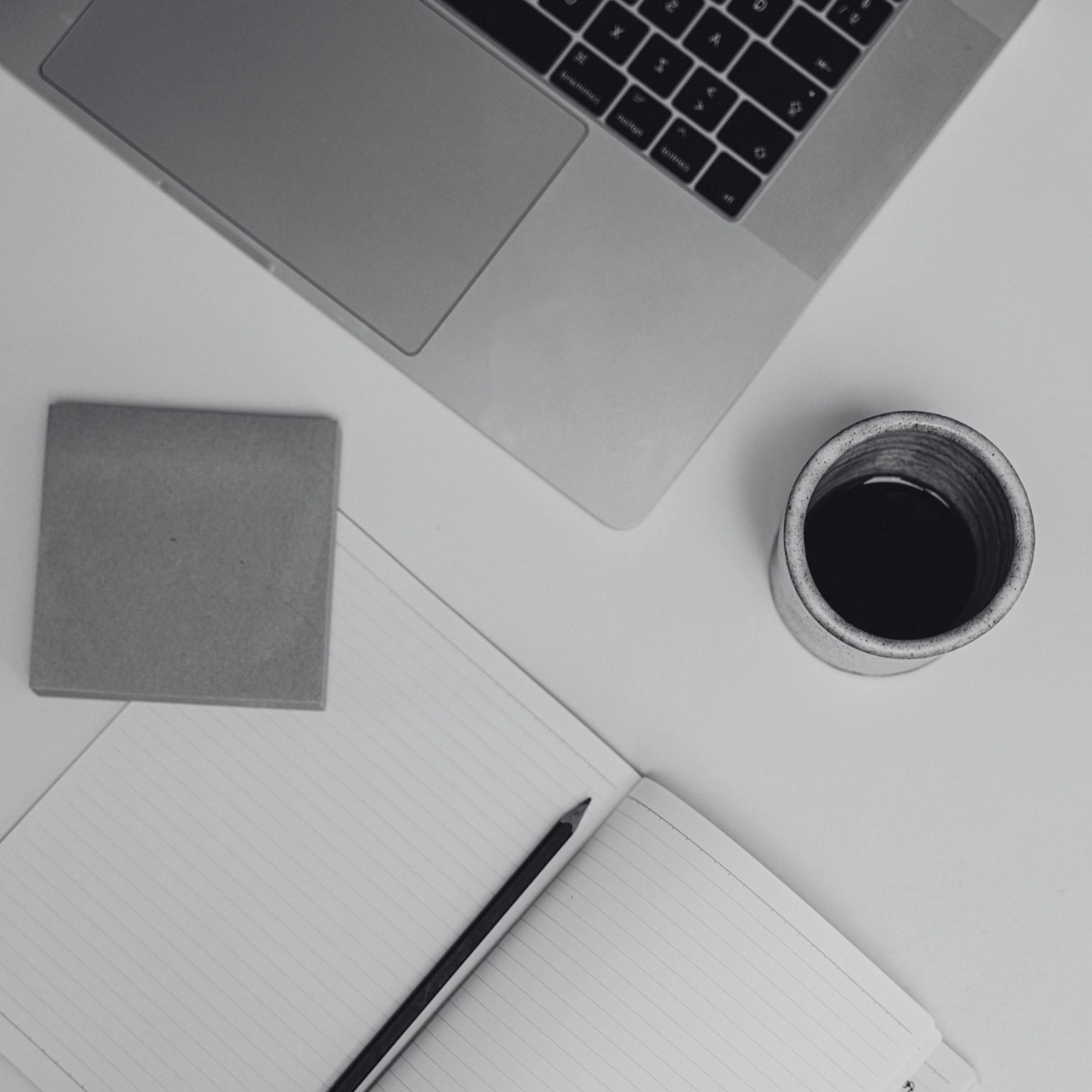 Clean desktop with laptop, notebook, and coffee—capturing a focused moment of fashion consulting, planning, and productivity.
