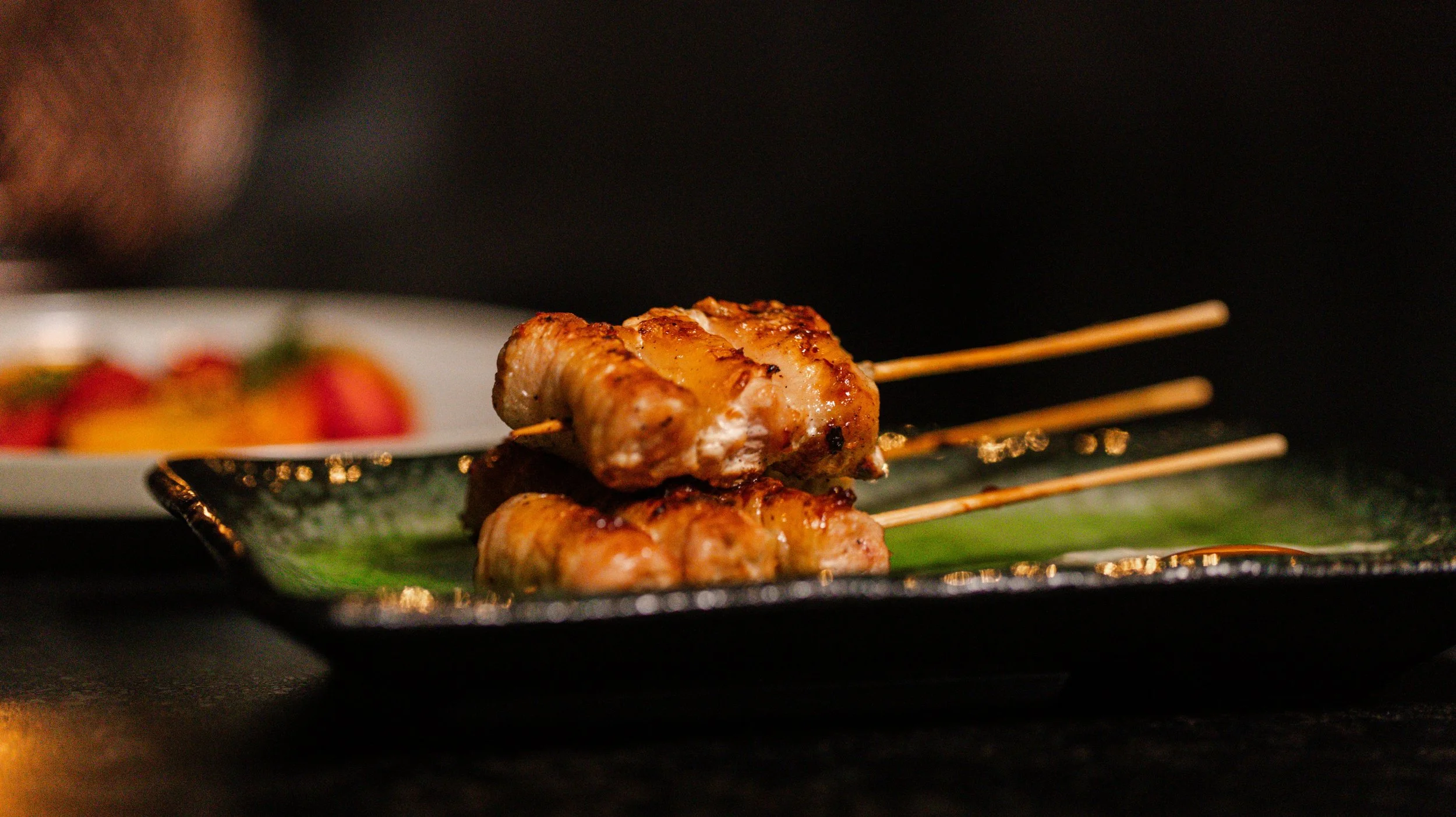 A professional close-up of authentic Japanese grilled yakitori skewers, showcasing the elevated shared plates and izakaya dining experience at Zōtō in Sarasota, FL.