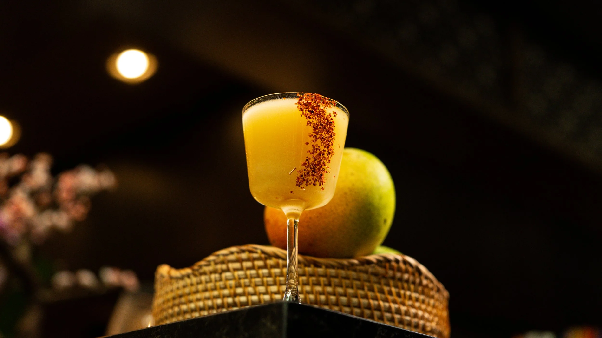 The 'Let that Man-Go' cocktail at Zōtō, a vibrant yellow mango-based drink with a spiced chili rim and fresh mango garnish.