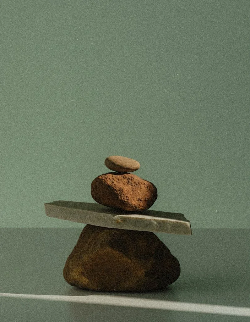 Stacked stones in balanced formation on a flat surface with a muted green background.