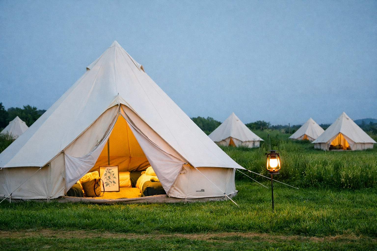 Tiendas de campaña blancas en un campo durante la noche con una linterna encendida cerca de ellas.