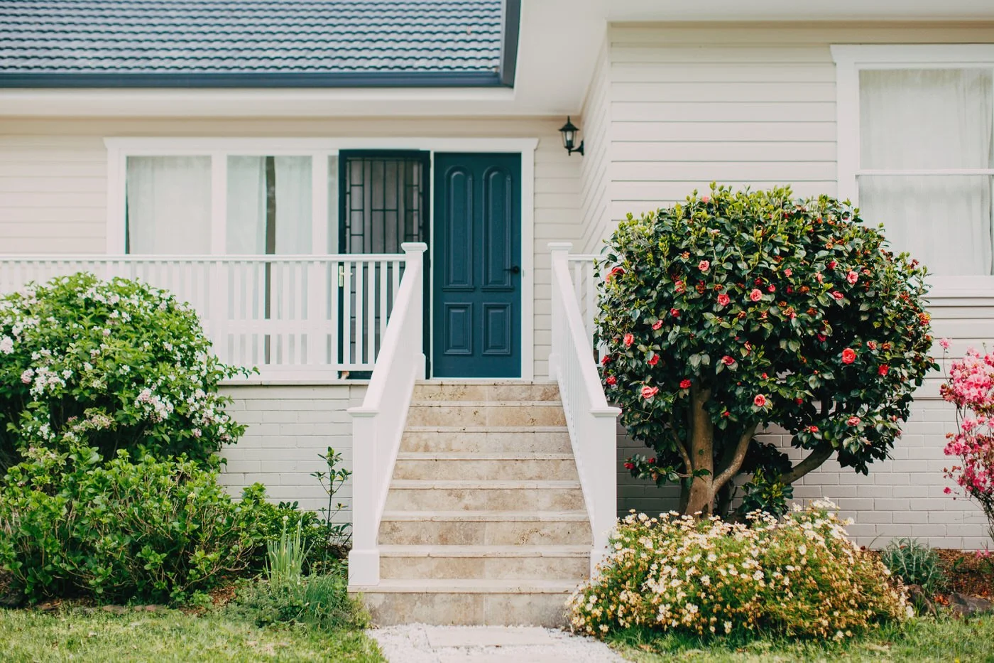 Elegant white house entrance with dark blue door and staircase surrounded by landscaped gardens at a Cherrybrook property with custom extension
