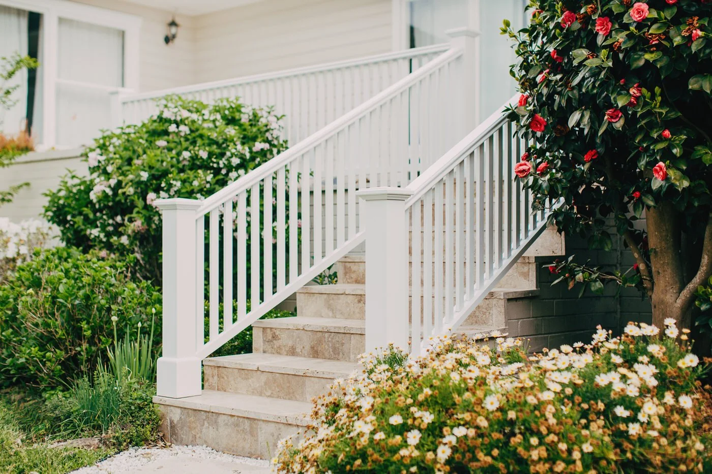 Elegant white porch entrance with stone steps and flowering garden, example of refined detailing in custom extensions in Hills District by AGATHĒ