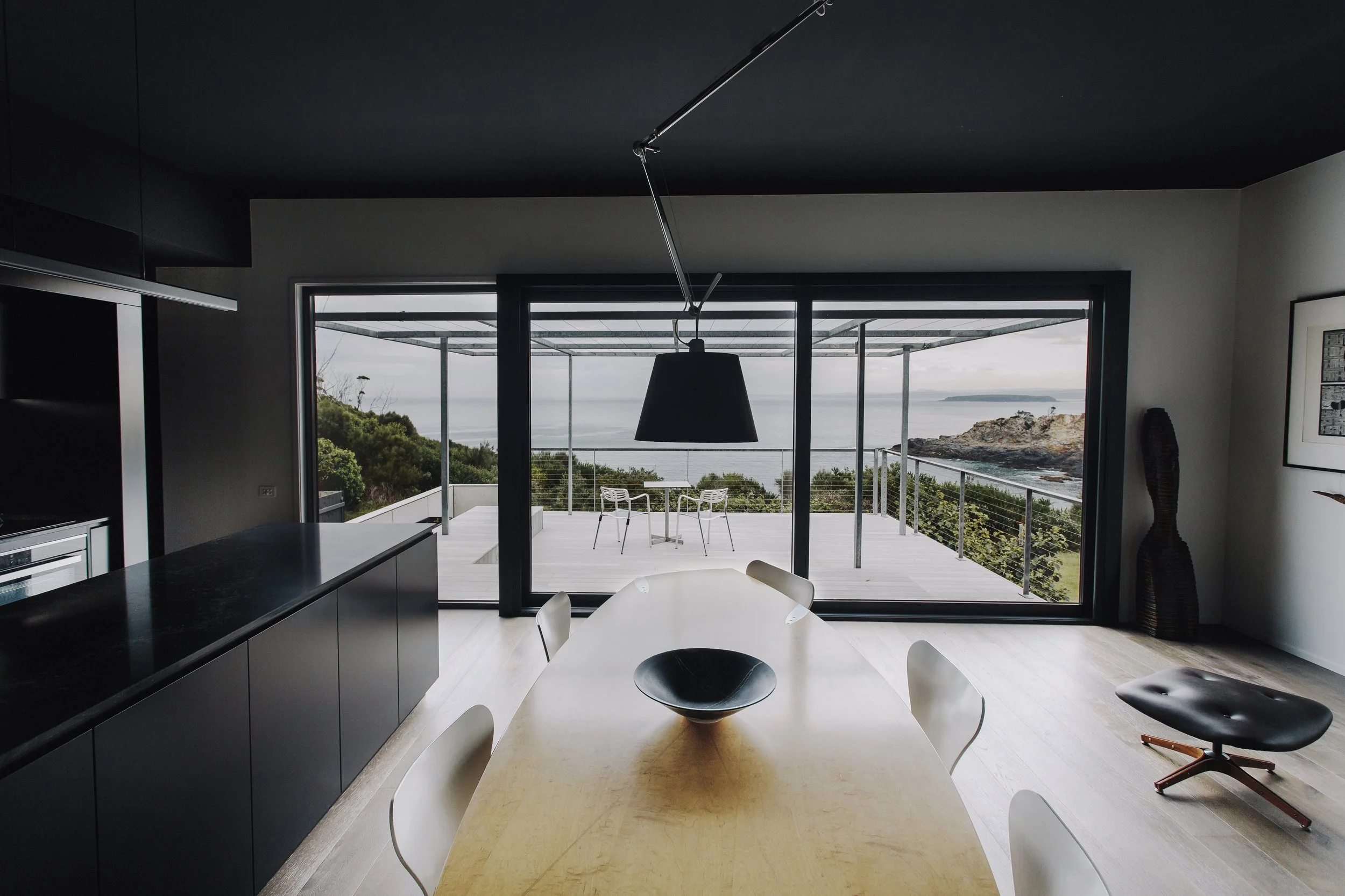Elegant dining area with panoramic glass doors framing coastal vistas, reflecting the premium design approach used in granny flats in Cremorne Point renovations