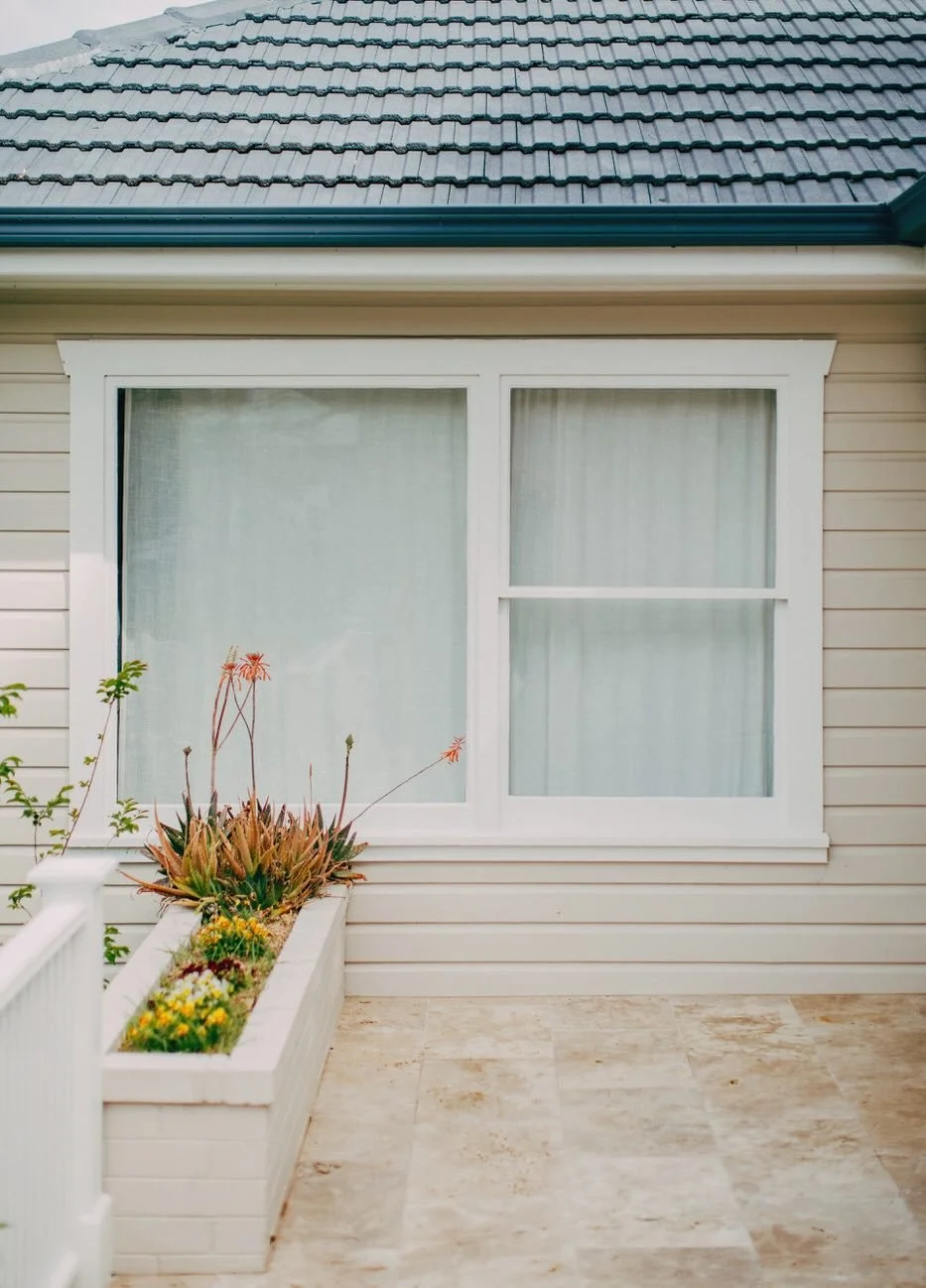 House exterior featuring large window, dark shingled roof and white planter with succulents—part of a premium custom extension in Castle Hill