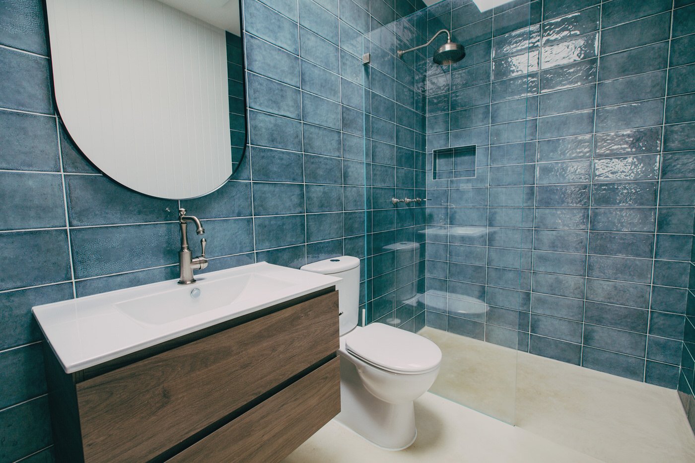 Modern bathroom featuring blue subway tiles, timber vanity and round mirror in a luxury Hills District custom extension